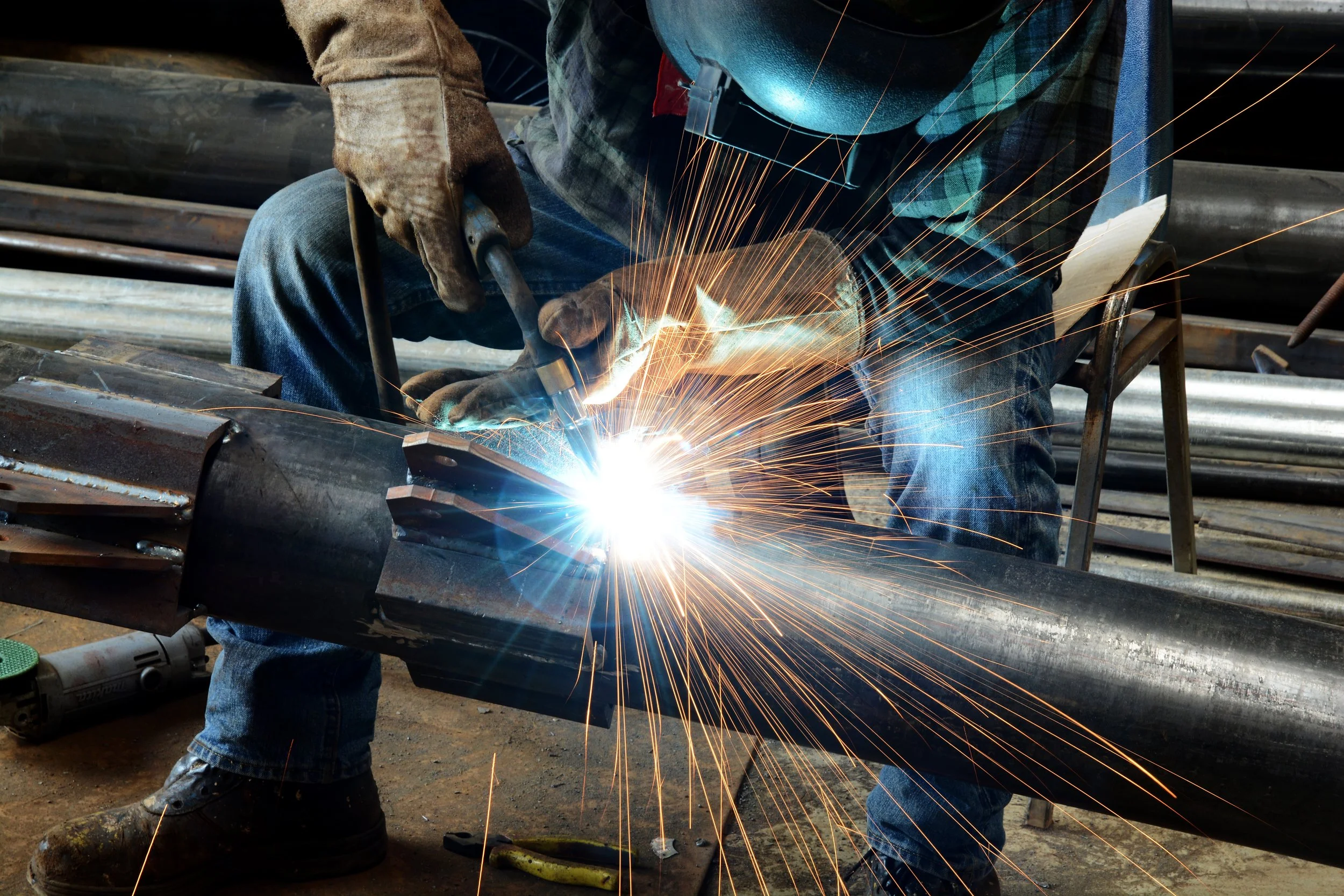 A worker welding metal pipes together with sparks flying as the welding torch heats the metal. He found the right fit through working with a welding recruiting service.