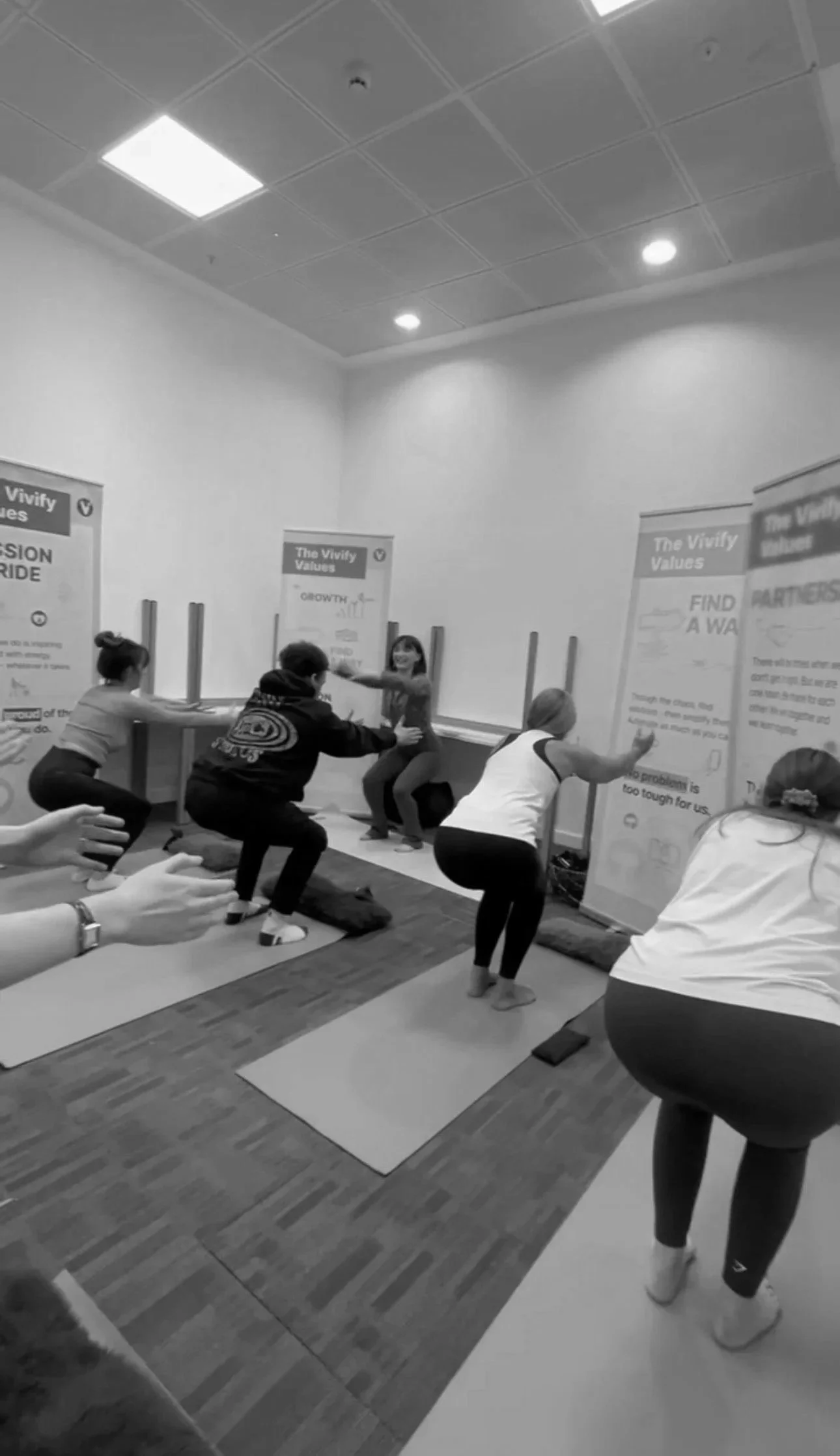 People participating in a yoga or exercise class in a room with posters on the walls.