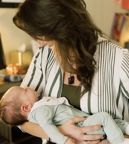 Woman holding a newborn baby indoors.