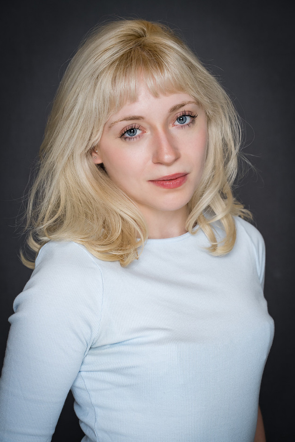 Photo of actress Mara Jade Koenig with blonde straight hair, wearing a light blue shirt.