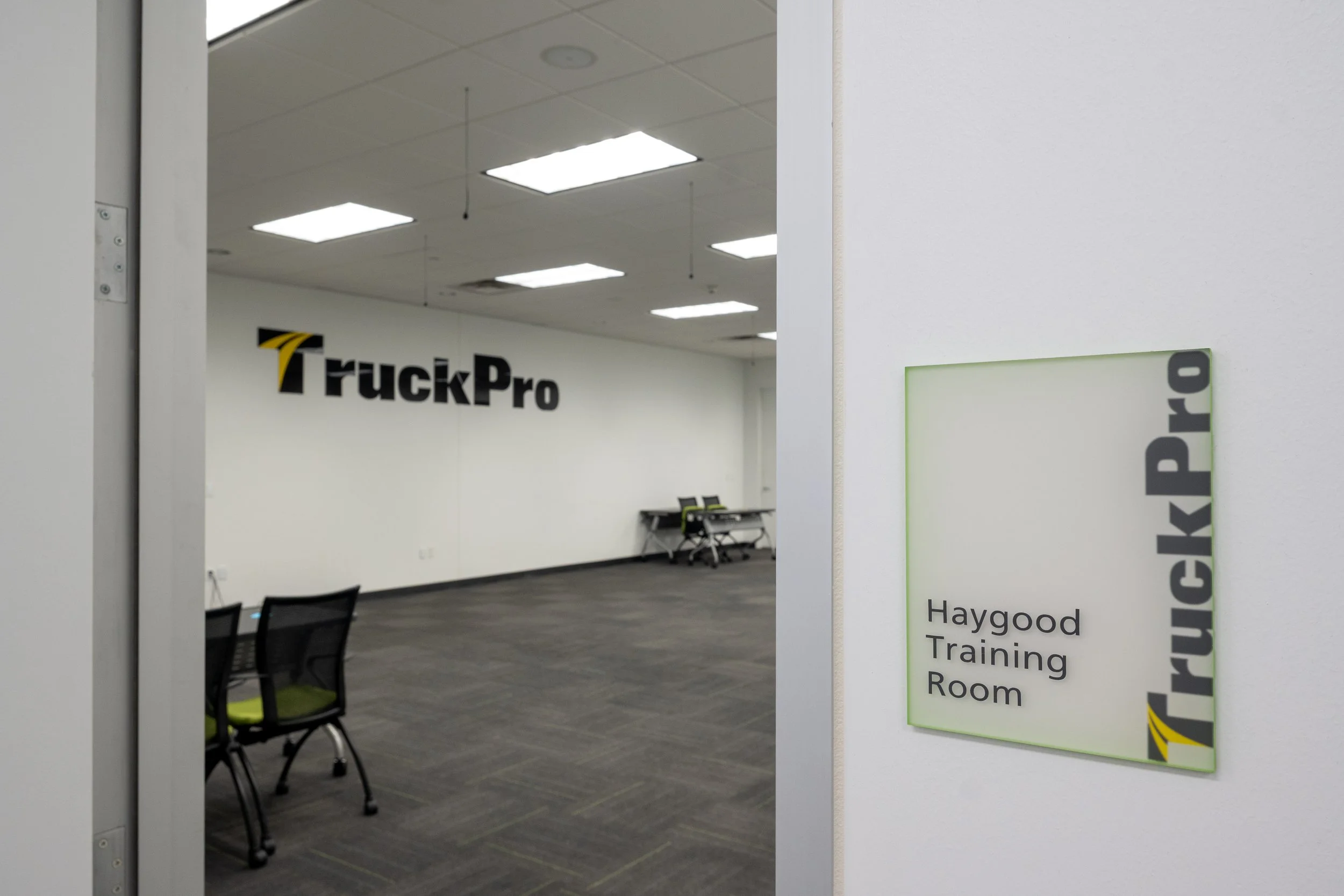 View of an indoor training room seen through a doorway, with chairs arranged around the room and a sign on the wall indicating it is a trucking room at Haygood.