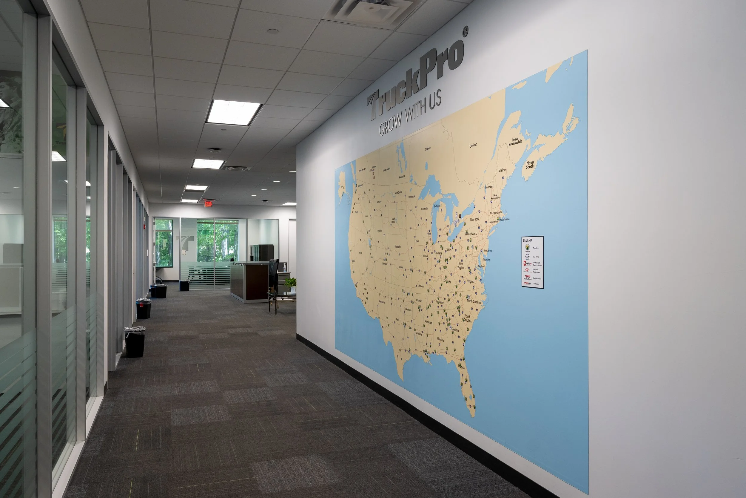 Office hallway with a large map of the United States on the wall, featuring the company logo 'TruckPro' and the slogan 'Grow With Us.'