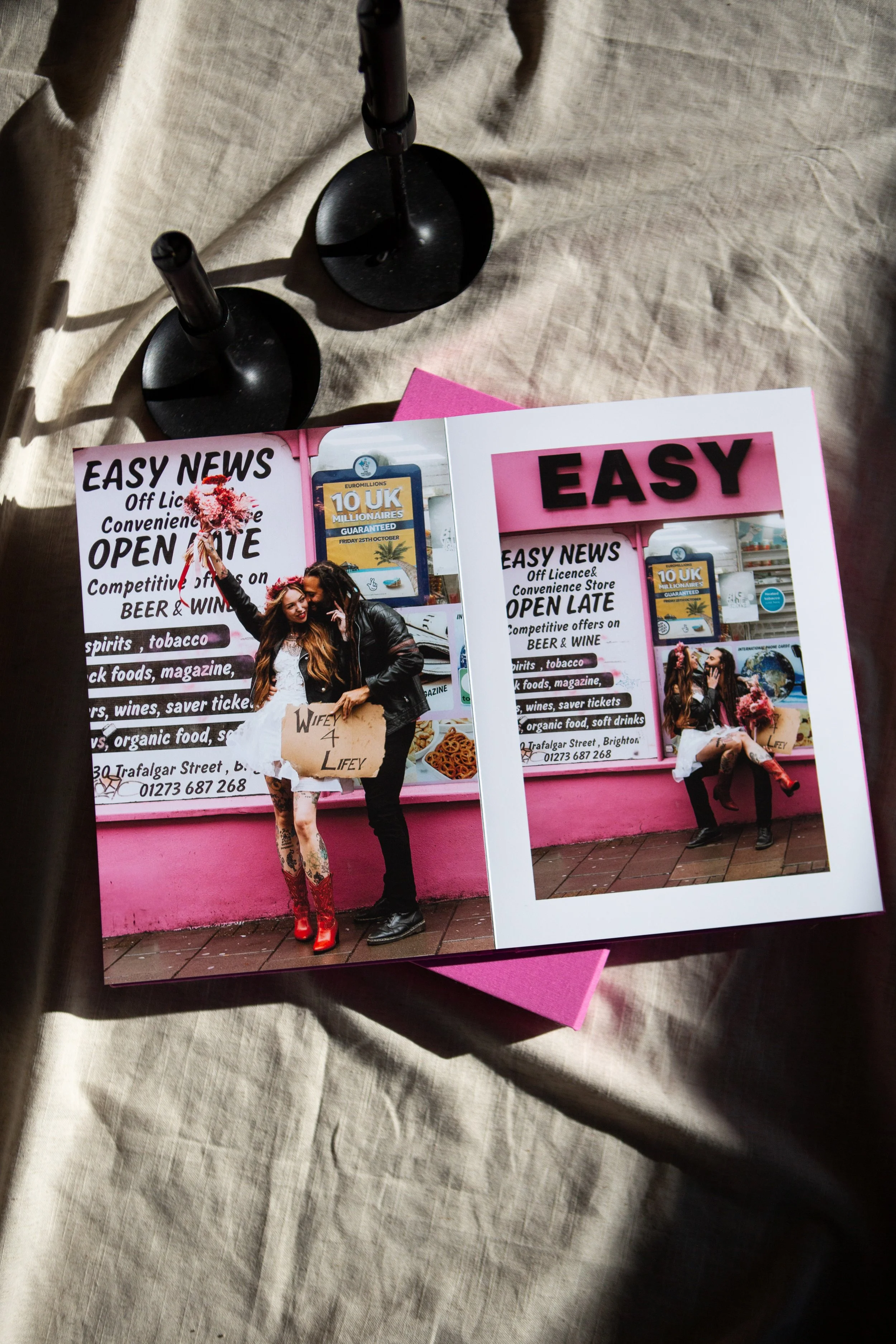Photograph of a flyer and a picture on a table. The flyer promotes an open late convenience store with various products listed, including alcohol, tobacco, snacks, and organic food. The picture shows two women posing outside the store, one holding pi