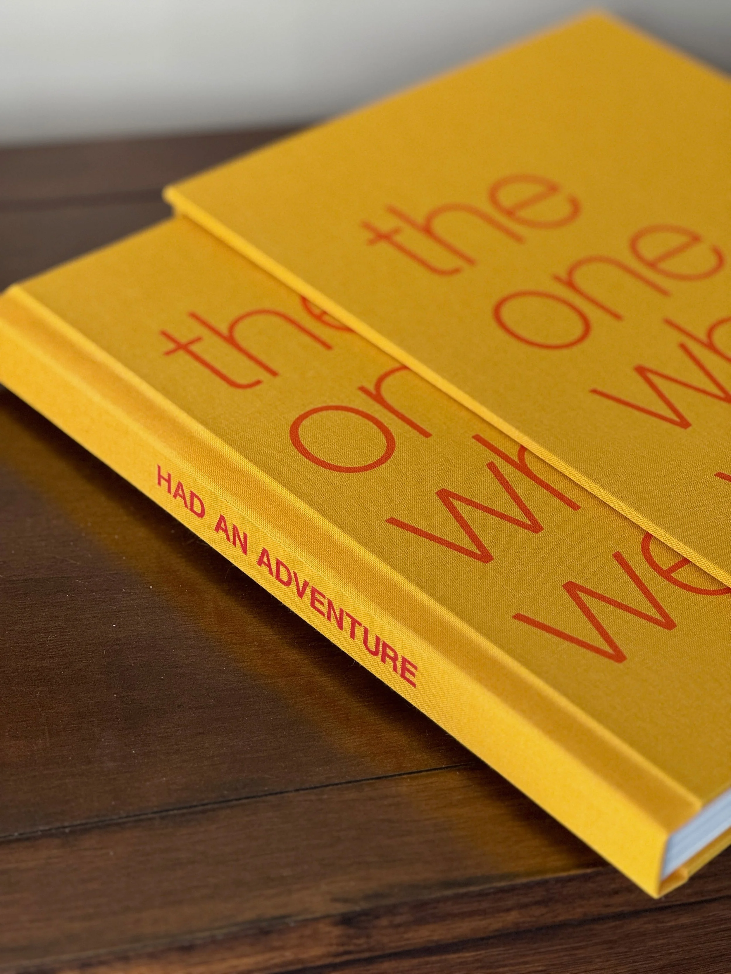 Close-up of two yellow books titled 'the one who had an adventure' stacked on a wooden surface.