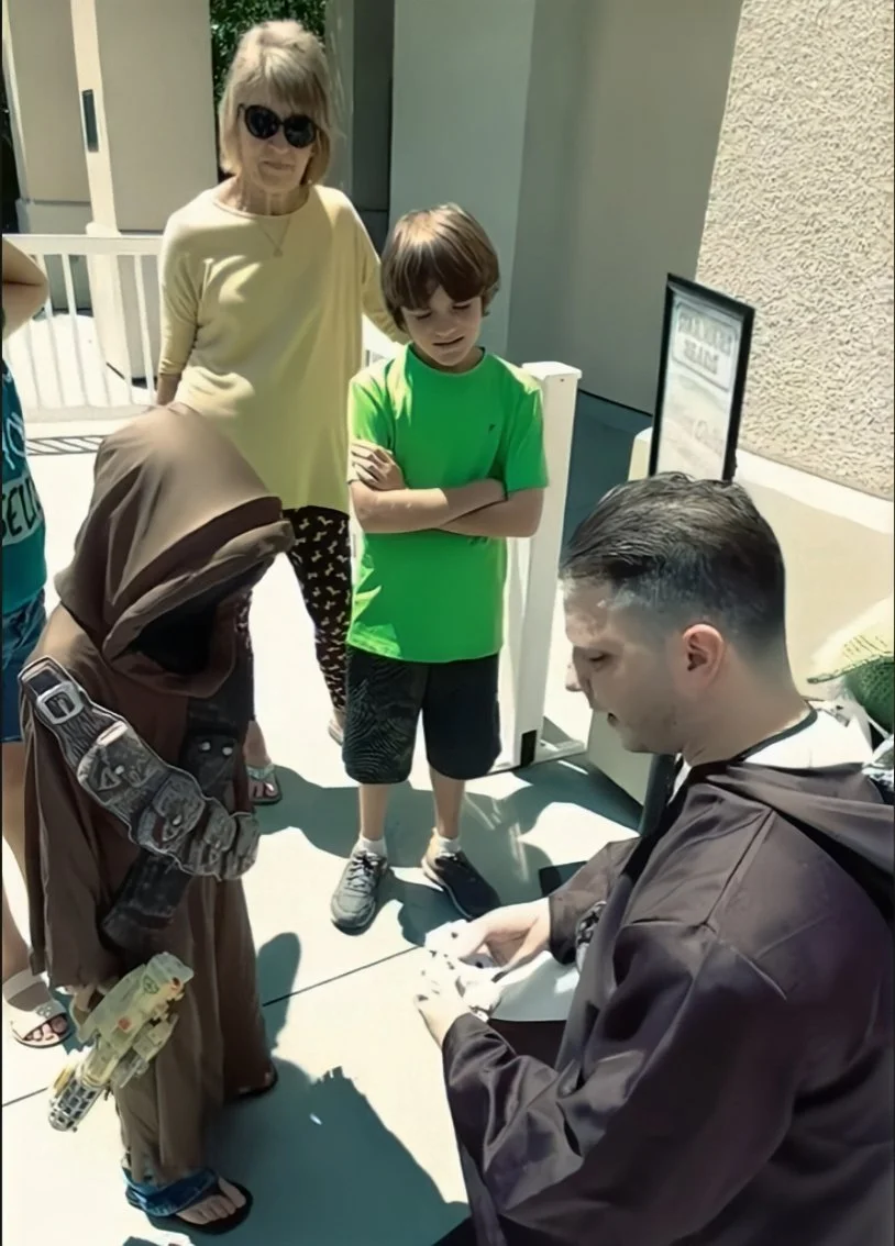 John performs a card trick as Obi John Kenobi for a child  dressed as a Jawa