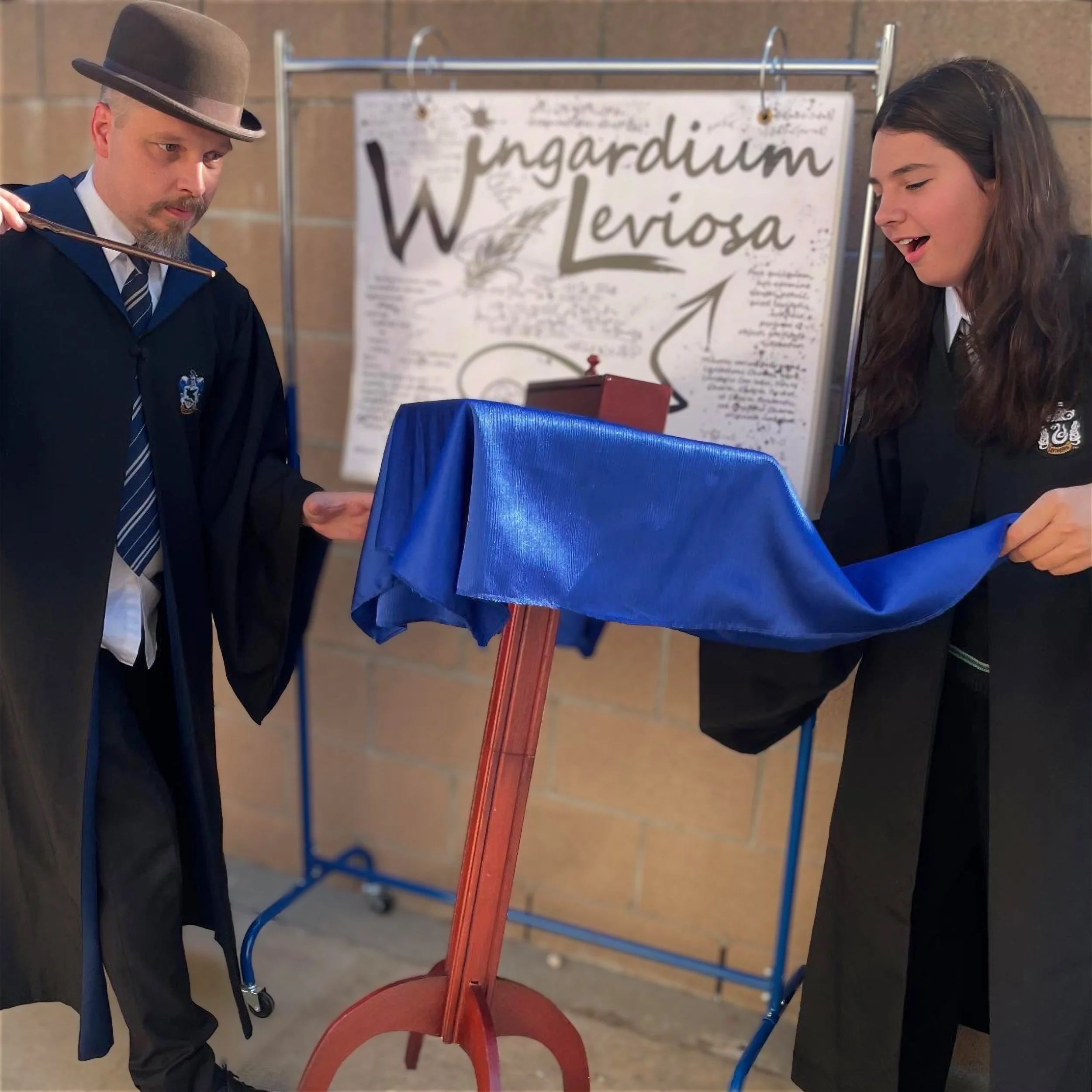 John with his assistant Miss Maizy in a promo photo floating a table with Wingardium Leviosa. 