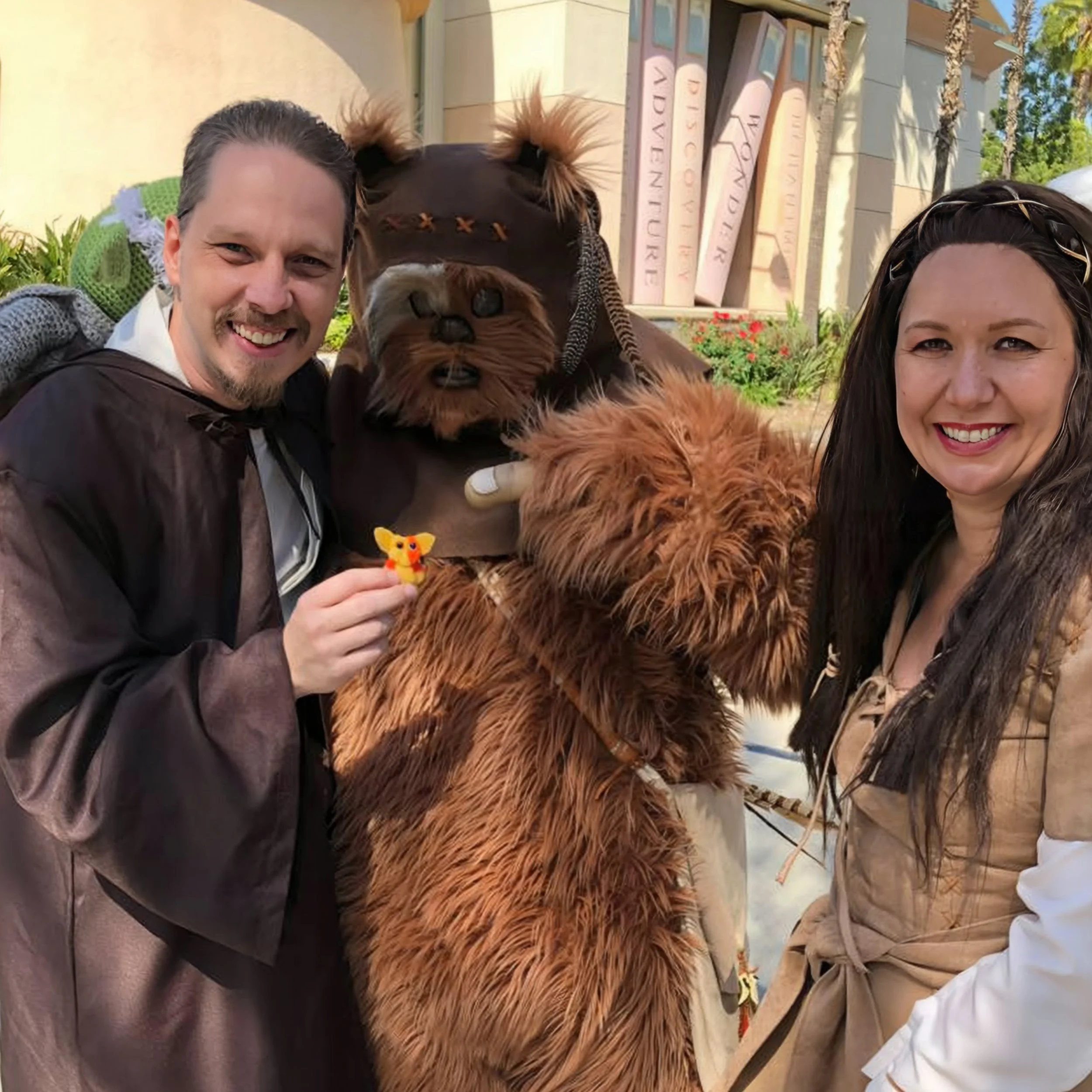 Two people in costumes posing with two dogs dressed in costumes during a festive outdoor event.