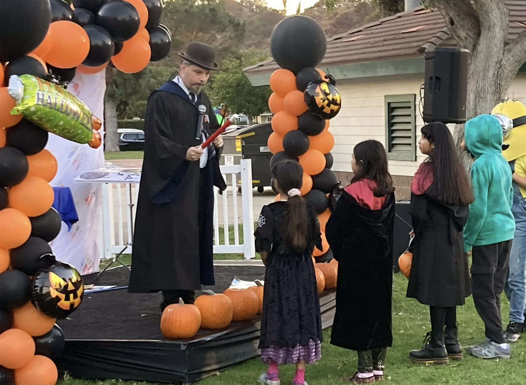 John on stage at Duartes Halloween Howl in his Ravenclaw robe with several assistants to attempt a magic effect. 