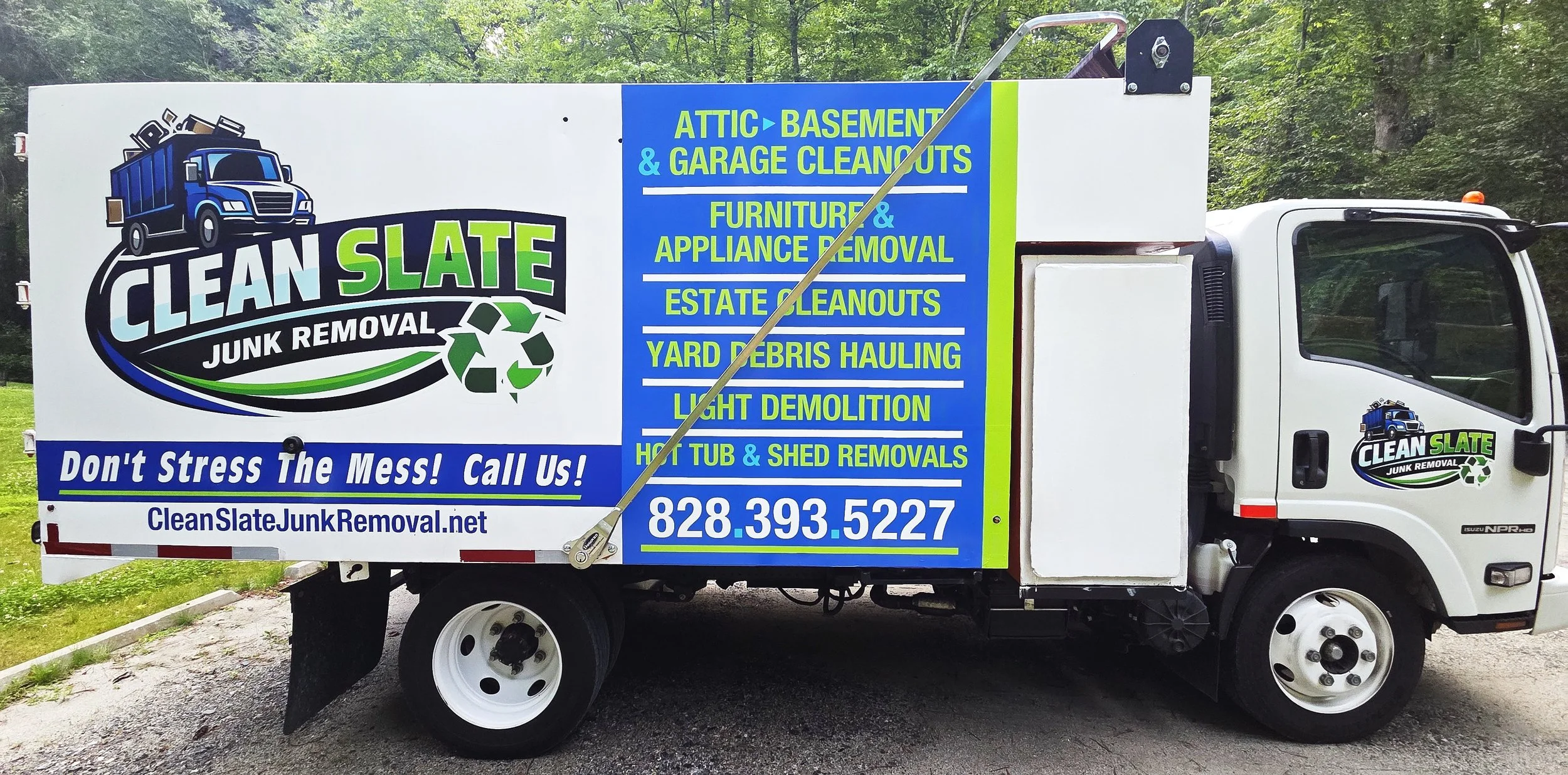 A white truck with a large colorful sign for Clean Slate Junk Removal on its side. The sign features the company logo, a blue trash truck with a recycling symbol, and lists services such as attic, basement, garage cleanouts, furniture, appliance removal, estate cleanouts, yard debris hauling, light demolition, hot tub, and shed removals. The sign also has the company website and phone number.