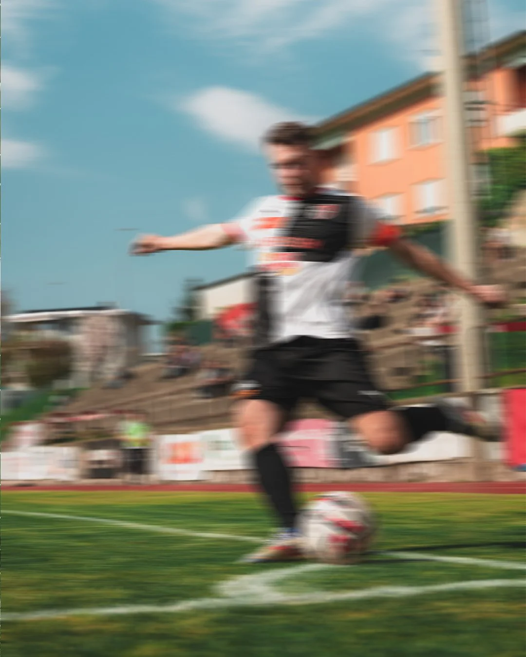A soccer player in black shorts and a white jersey kicking a soccer ball on a field during a game.