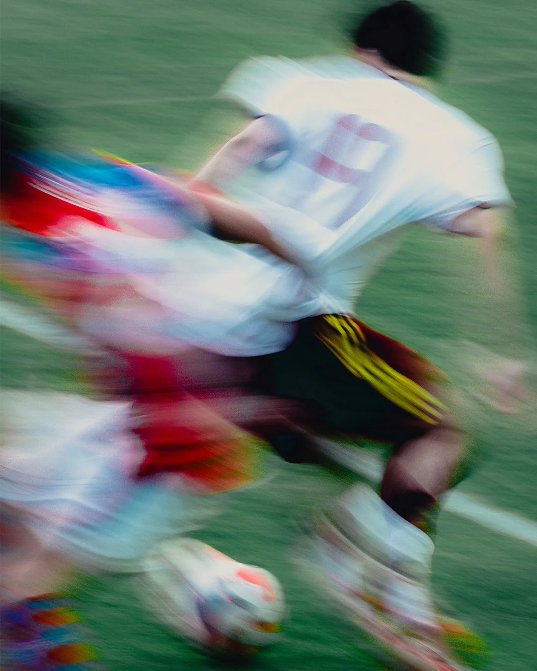 A person wearing a white shirt with a number on it, black shorts with yellow stripes, and colorful shoes, running on a field, captured with motion blur.