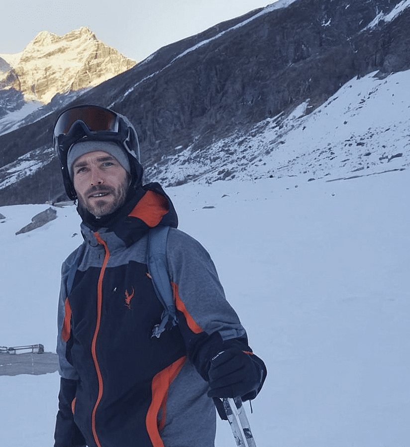Man in winter gear with a helmet and goggles in a snowy mountain landscape.