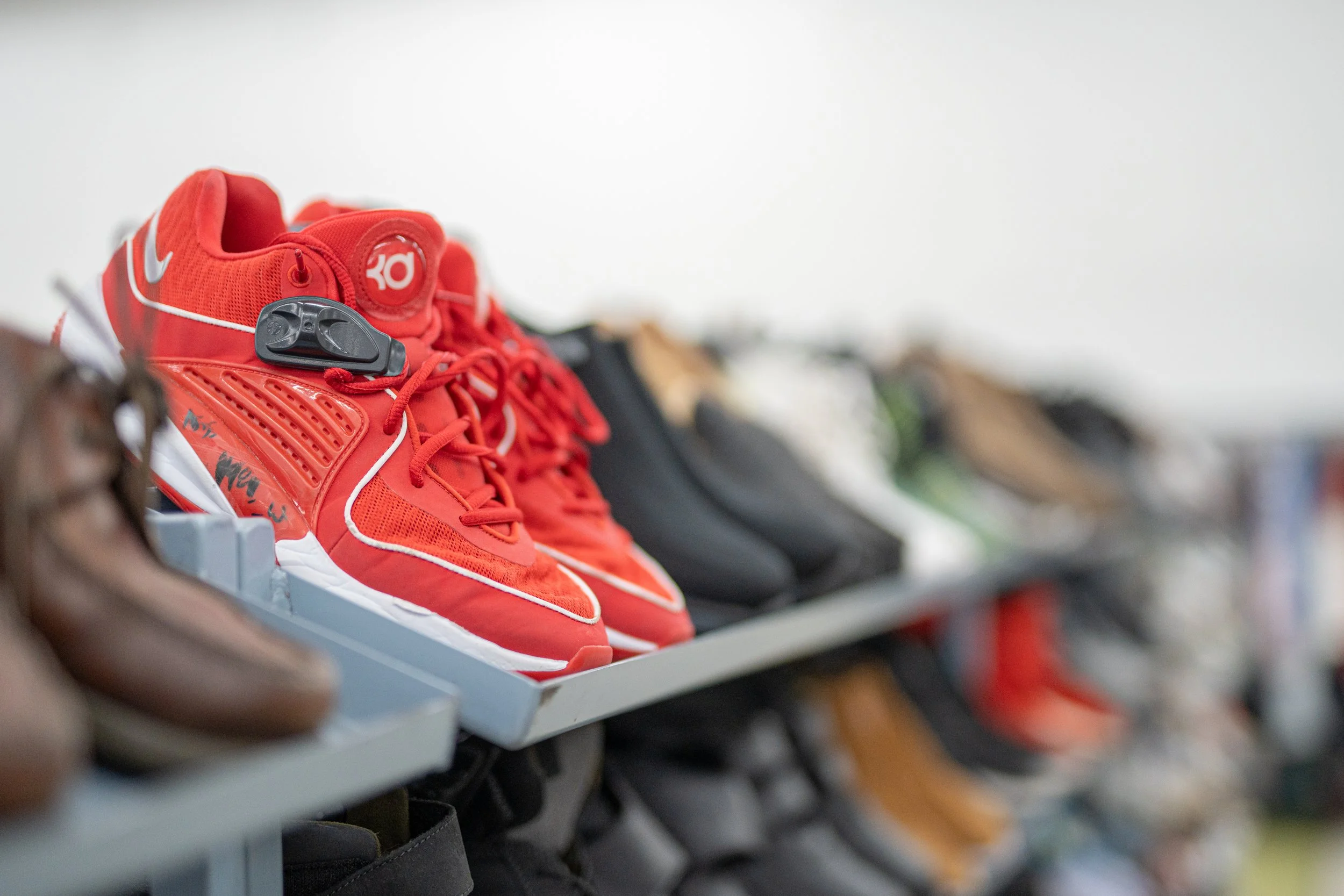 A close-up of a row of red athletic shoes on display on a shelf in a store.