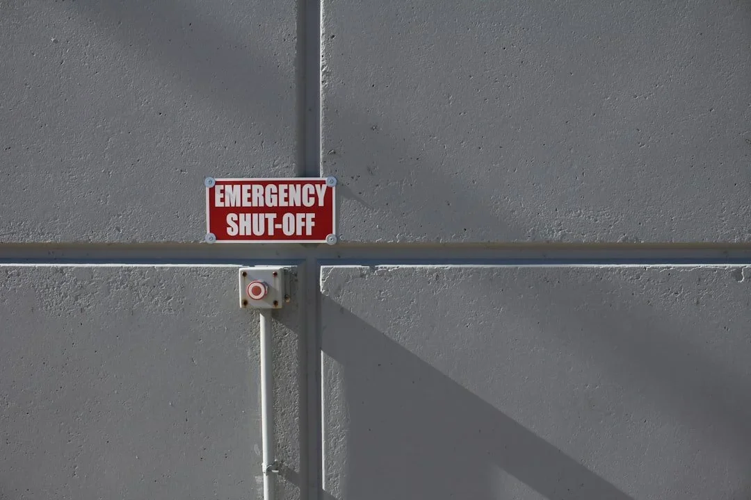 Gray wall with an emergency shut-off sign and a small control box.