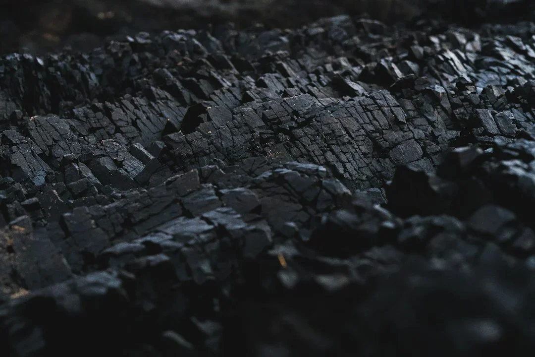 Close-up of black charcoal burned and cracked, showing its rough texture.
