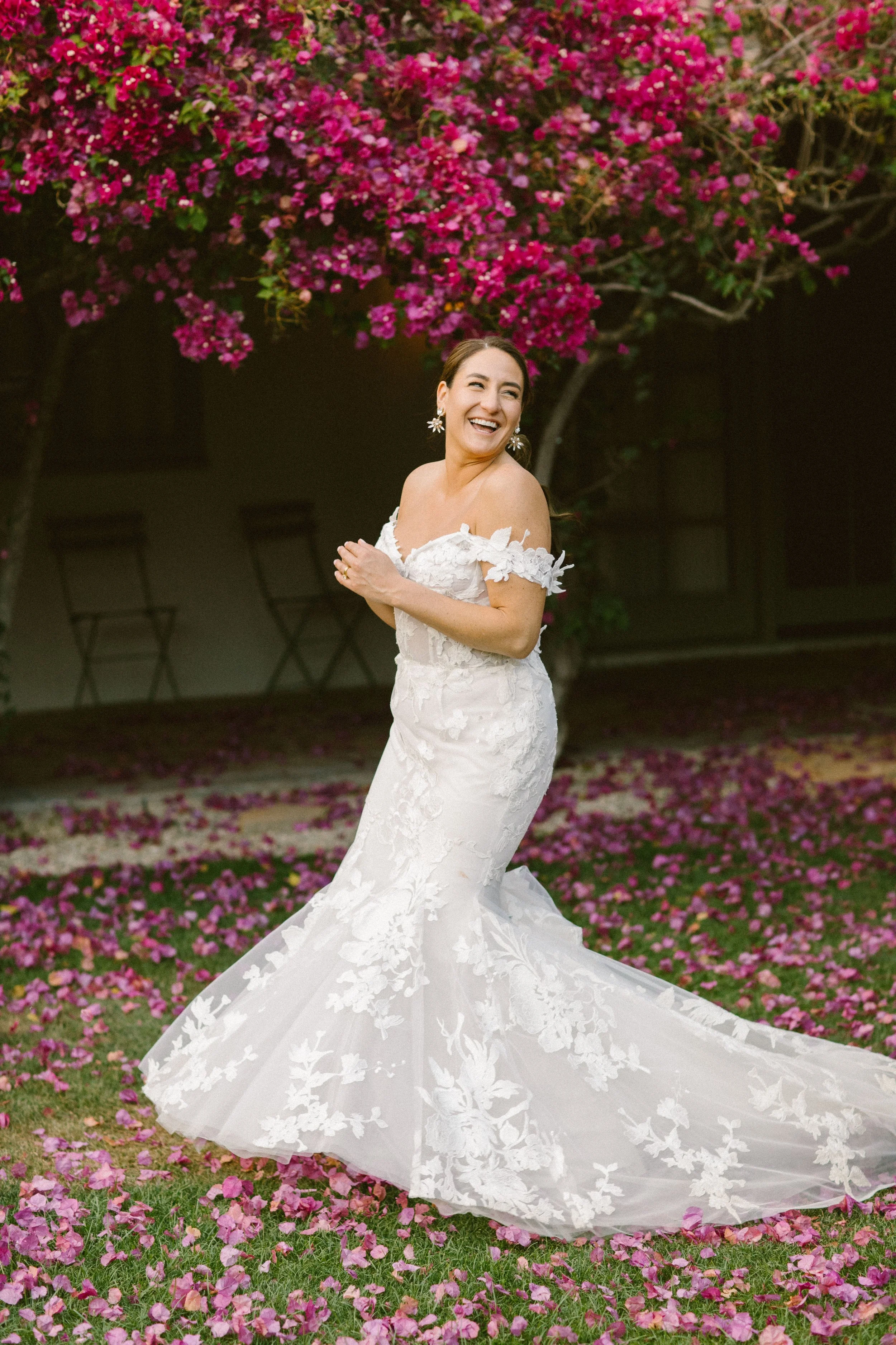 Bride dancing and laughing in front of bougainvillea.