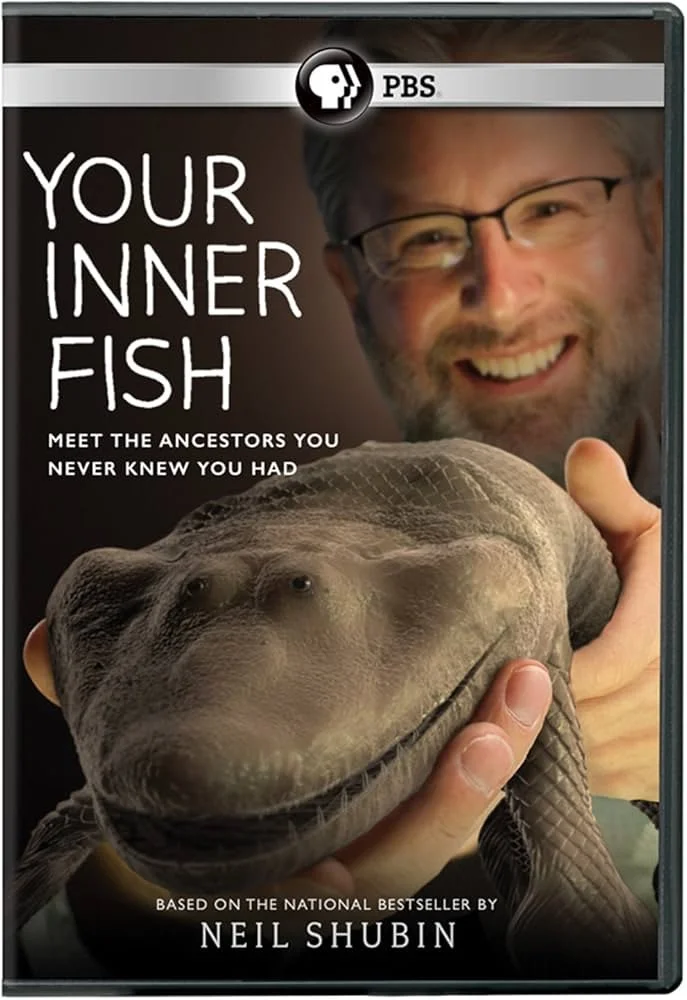 Book cover titled "Your Inner Fish" with a picture of a man smiling and holding a giant fish head, by Neil Shubin. PBS logo at the top.