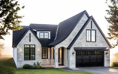 Modern two-story house with a black roof, stone exterior, and a black garage door, surrounded by a green lawn and trees.