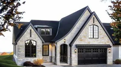 Front view of a modern two-story house with stone facade, large windows, a front porch, and a attached garage.