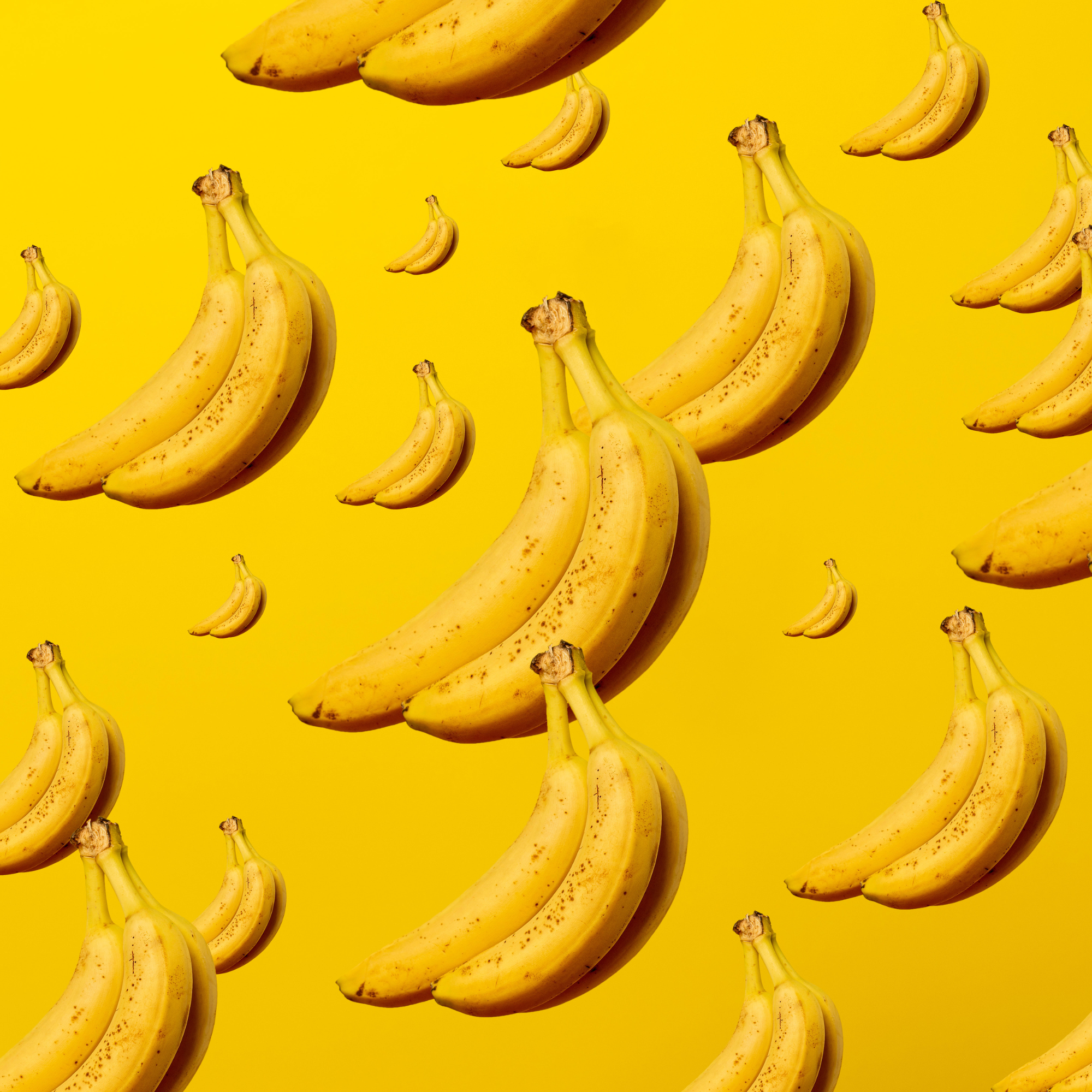 Multiple bananas floating against a bright yellow background.