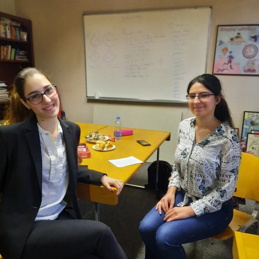Kalina Pavlović with professor seated at table during academic session, with notes and diagrams on whiteboard in background.