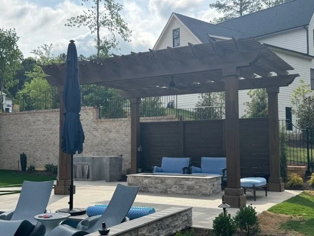 Backyard patio with a pergola, outdoor seating, a fire pit, and a brick wall.