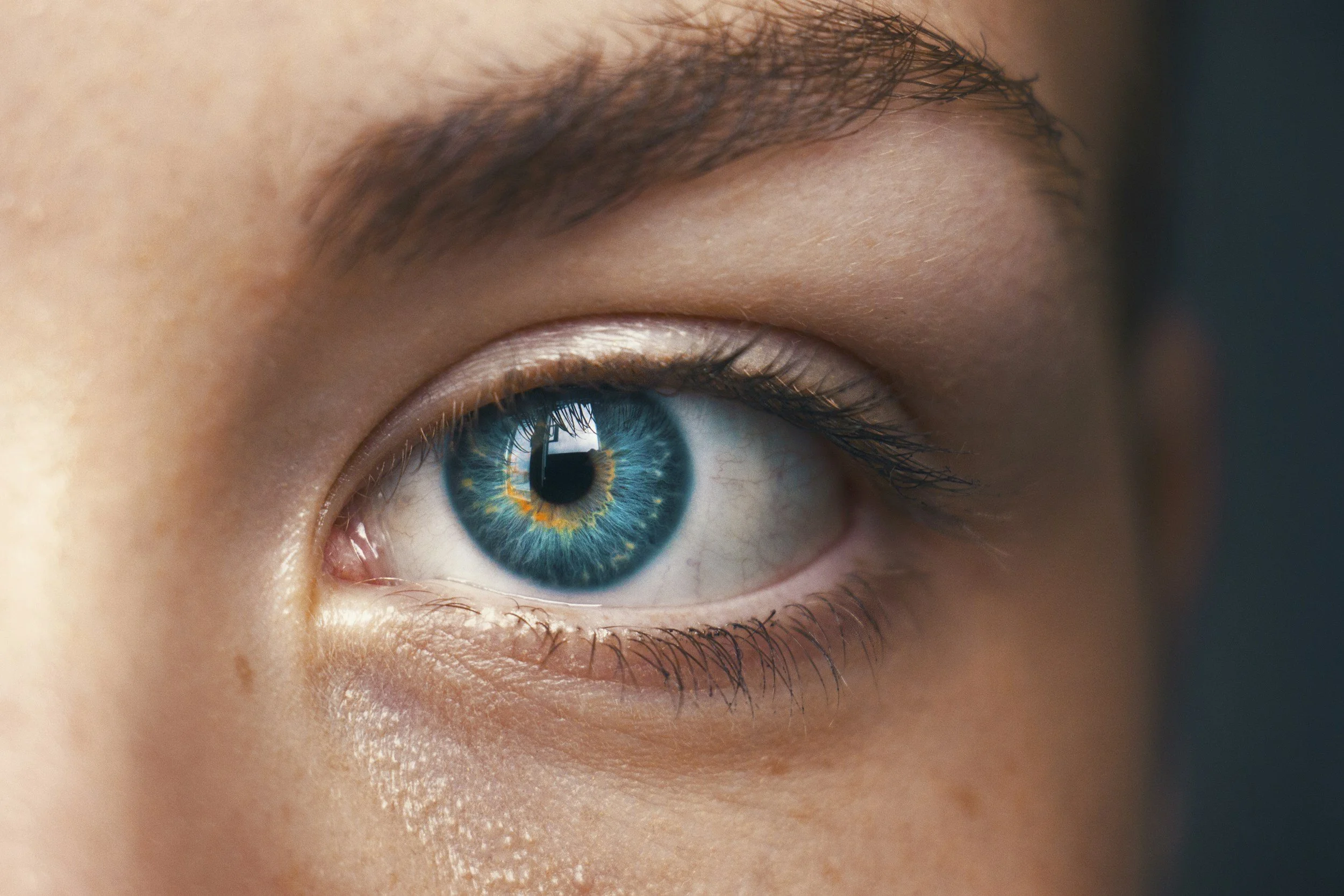Close-up of a human eye with a striking blue iris and intricate patterns visible in the iris.