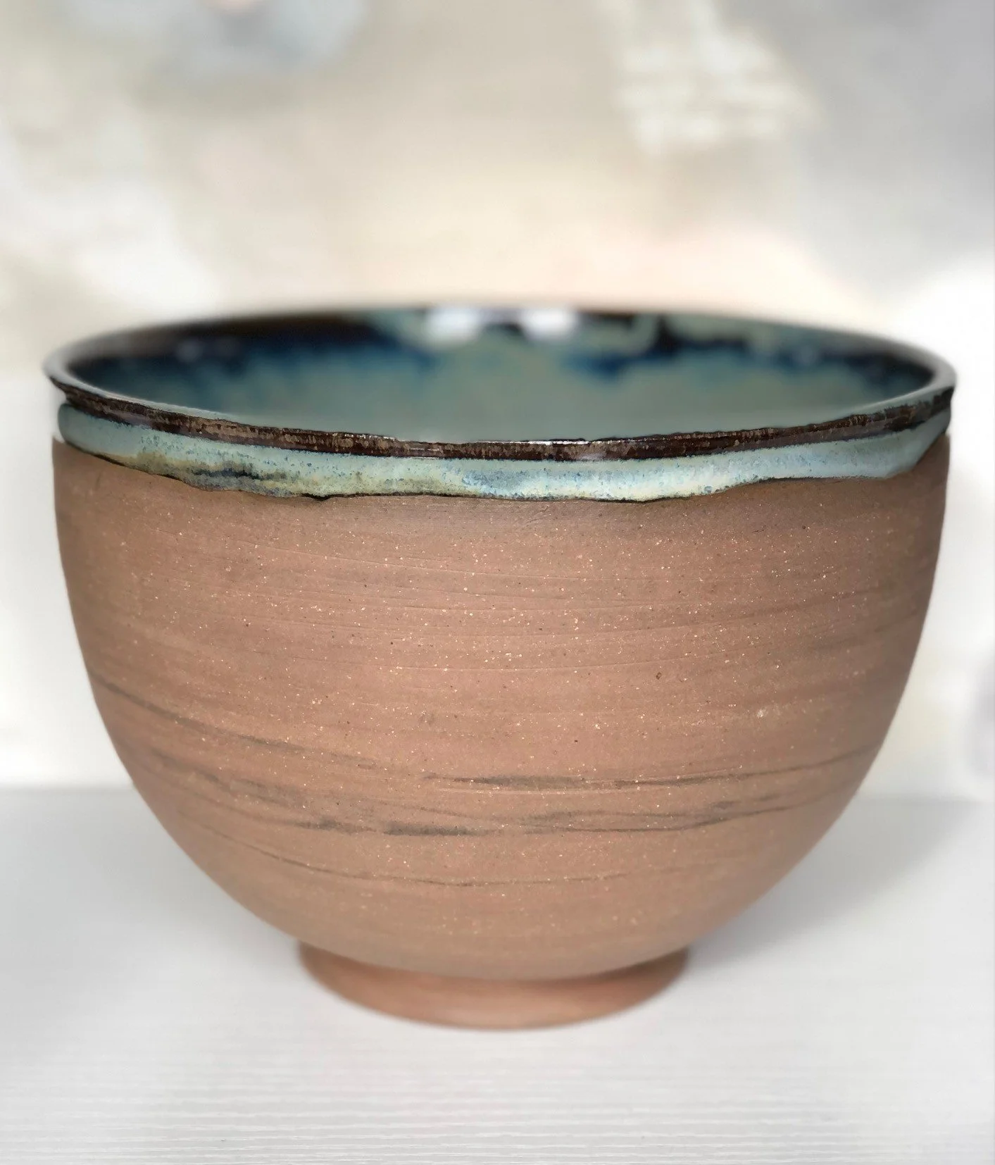 A ceramic bowl with a rustic, textured exterior and a glossy, blue interior glaze.