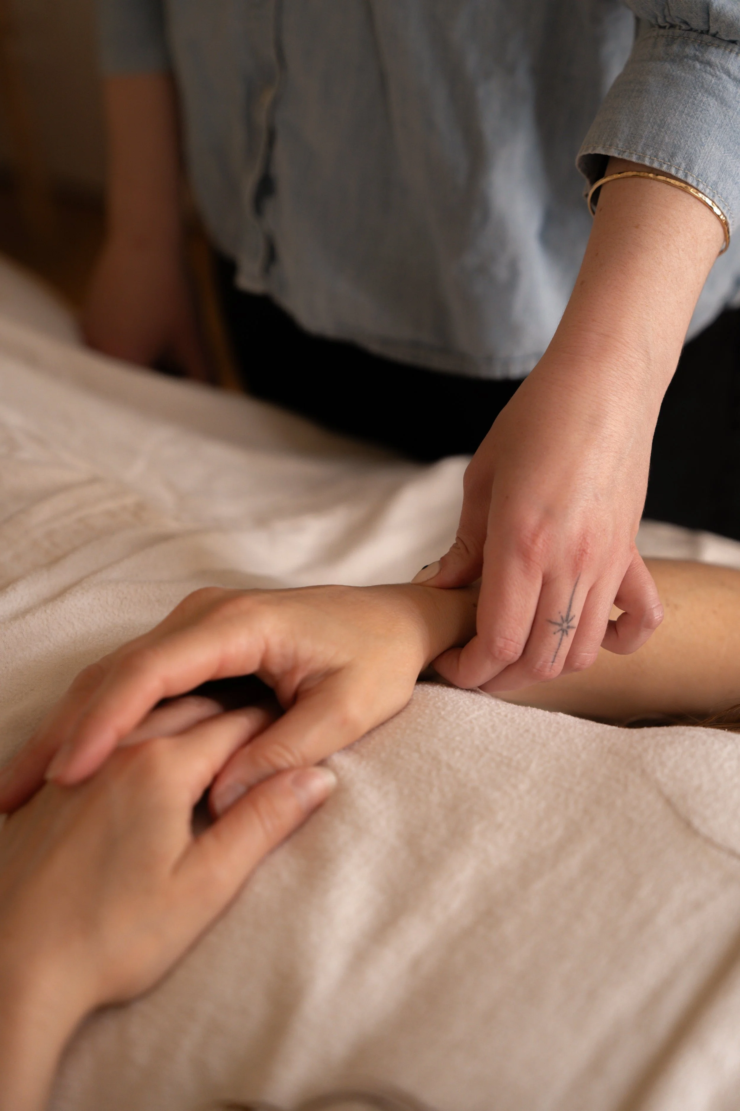 A person giving a massage to another person's hand on a beige surface.
