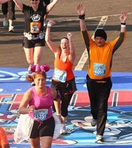 Marathon runners crossing the finish line with arms raised in victory.