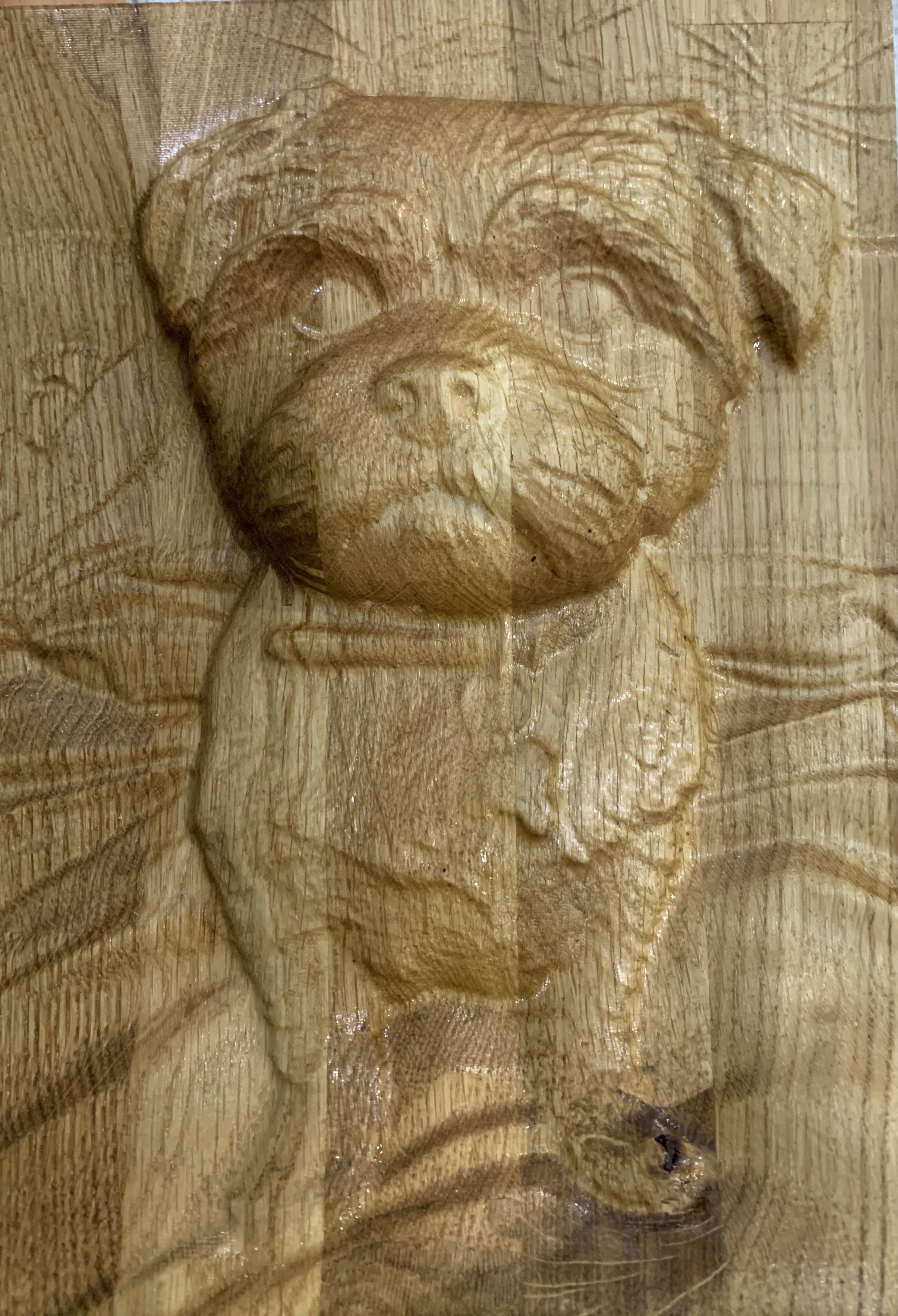 Wood carving of a dog's face on a wooden surface.
