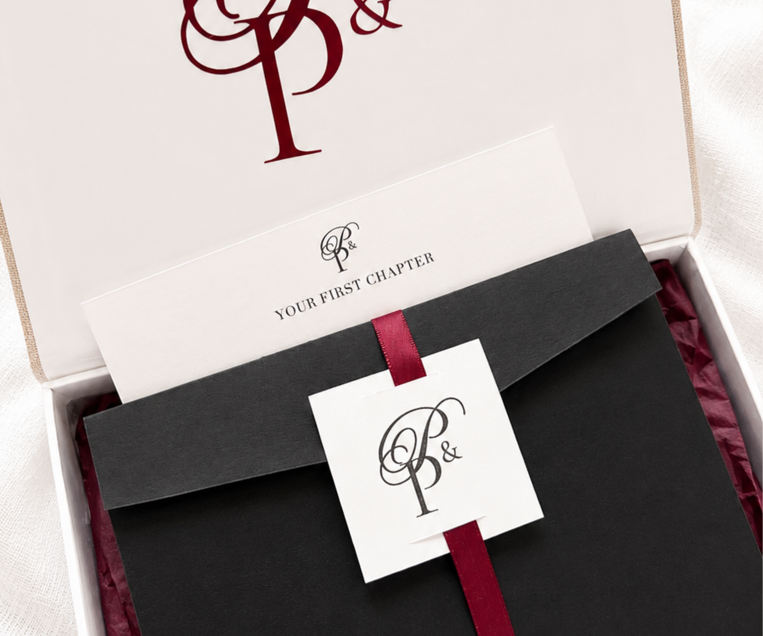 Paige & Press Sample Experience featuring a luxury keepsake box with custom monogram, black pocket folder, burgundy ribbon, and curated letterpress wedding stationery.
