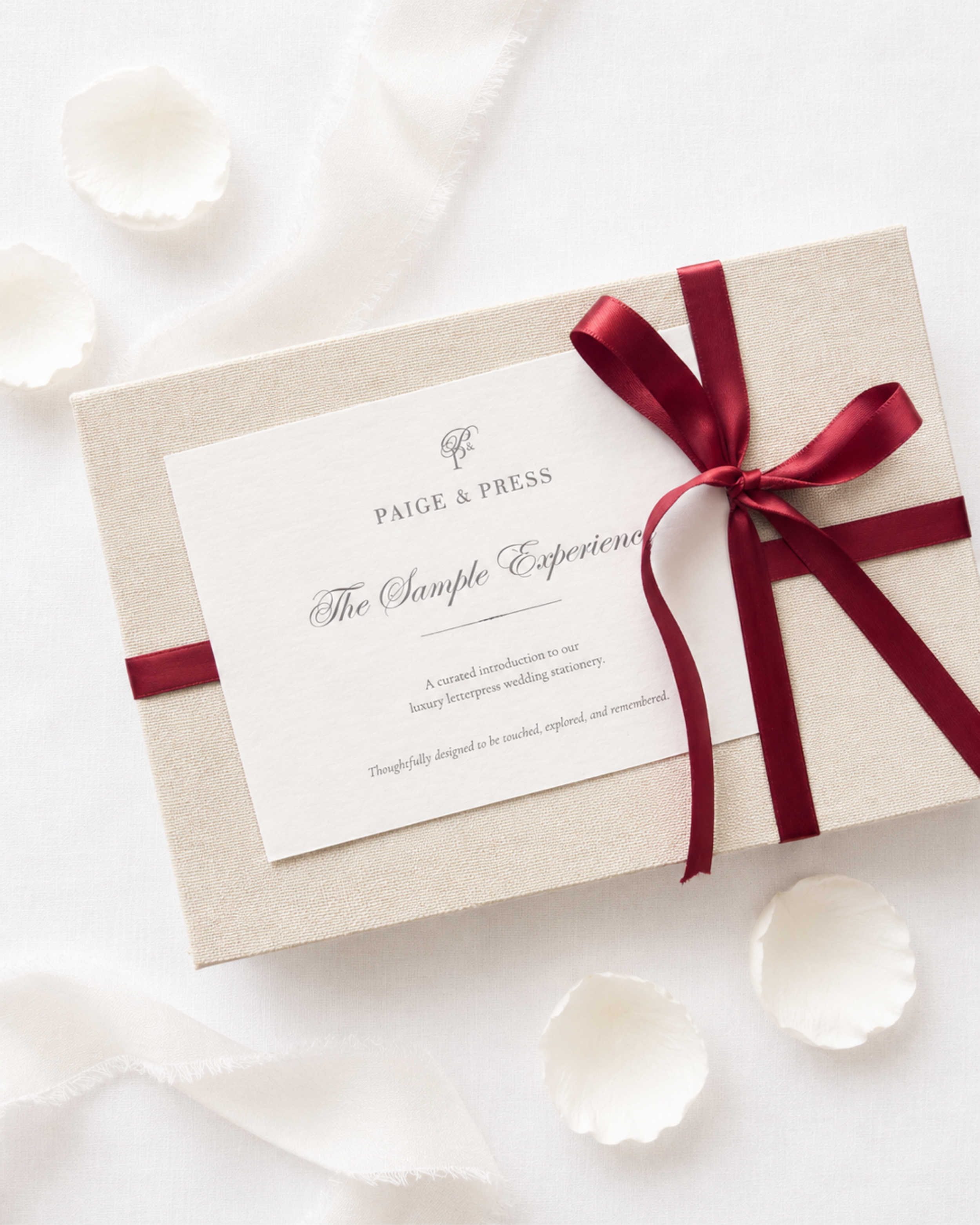 Paige & Press Sample Experience luxury wedding invitation sample experience wrapped with burgundy ribbon and premium letterpress stationery.
