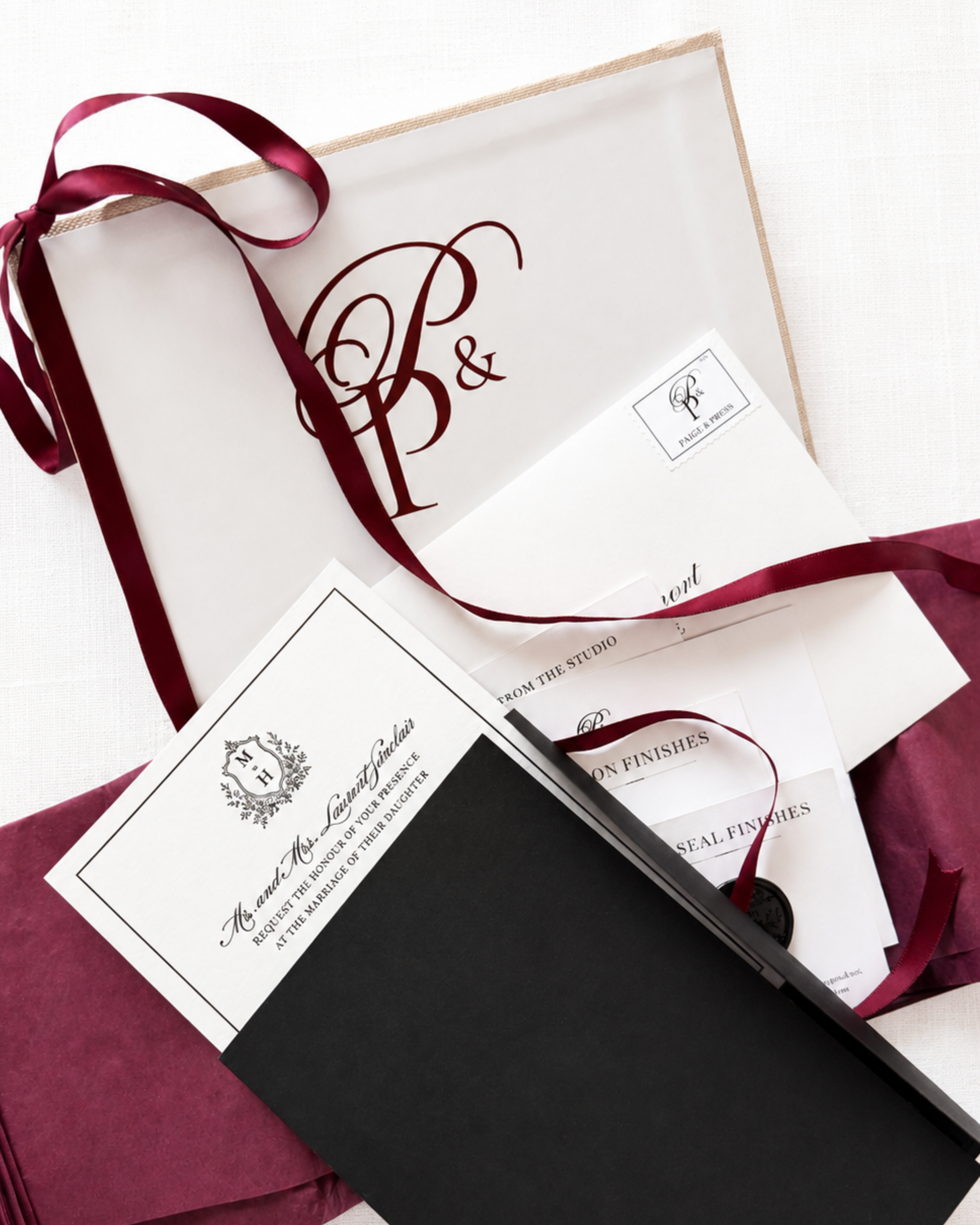Paige & Press Sample Experience featuring curated letterpress wedding stationery, custom monogram, black pocket folder, burgundy ribbon, and luxury invitation samples.