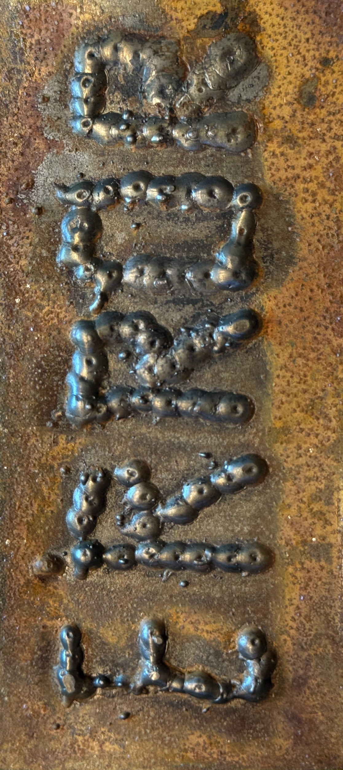 Close-up of welded metal letters spelling "ERROR" on a rusty metal surface.