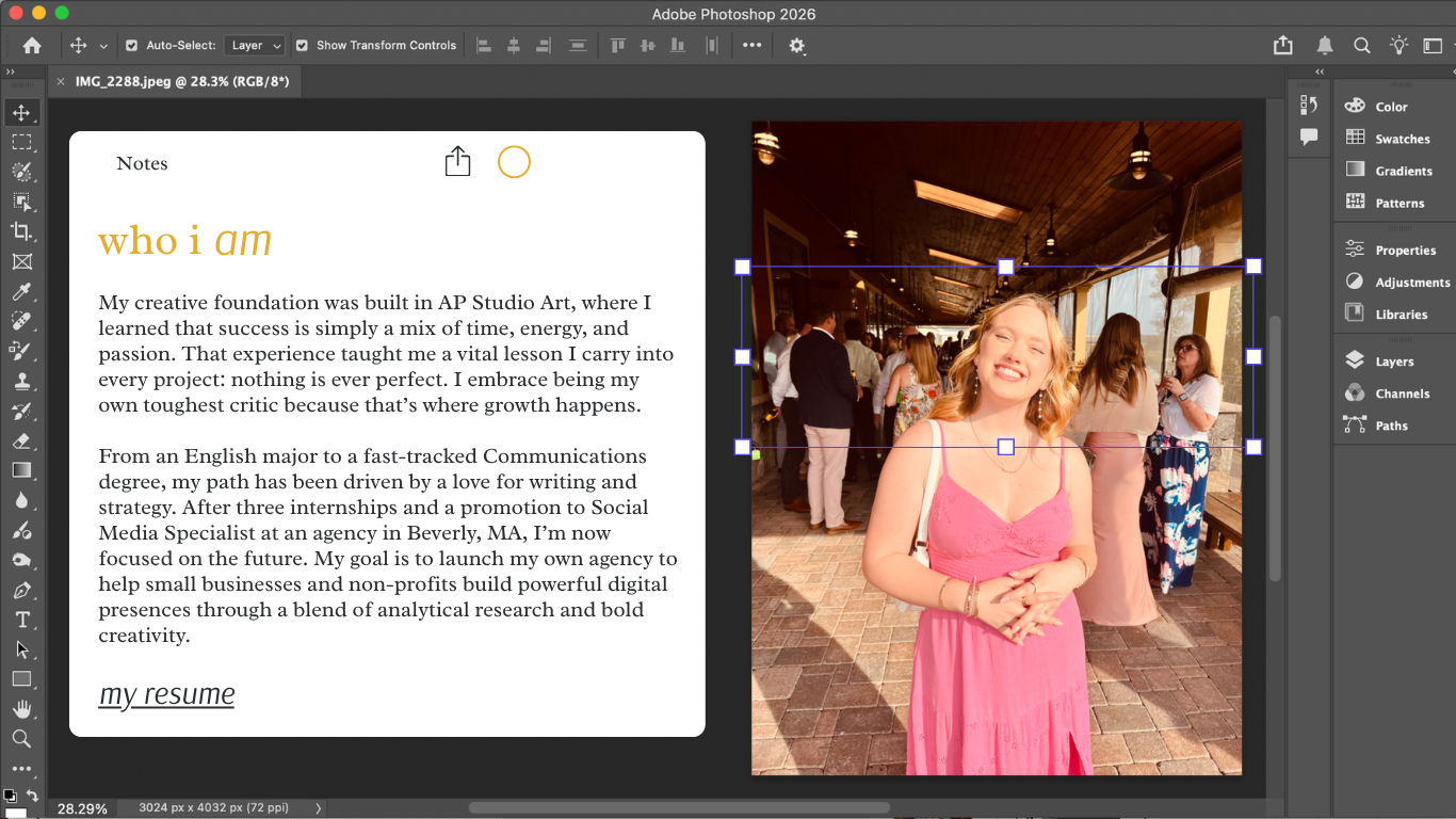 A woman in a pink dress smiling at a social event, with other guests in the background of a wooden-paneled room with large windows.