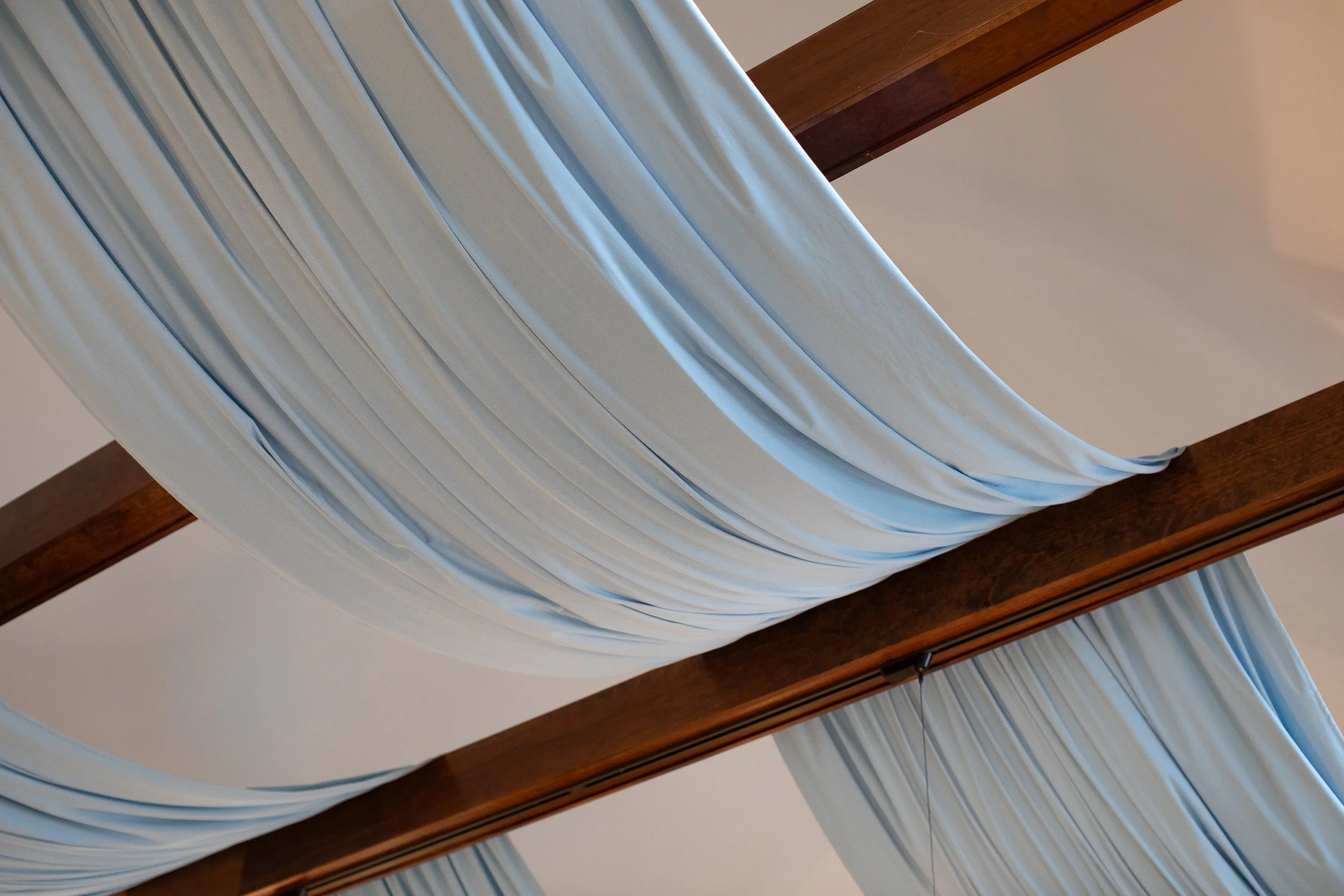 Light blue curtains hung over a dark wooden bed frame, draped elegantly in a bedroom setting.