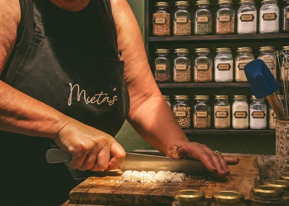 Person chopping white chocolate on a wooden cutting board in a kitchen.