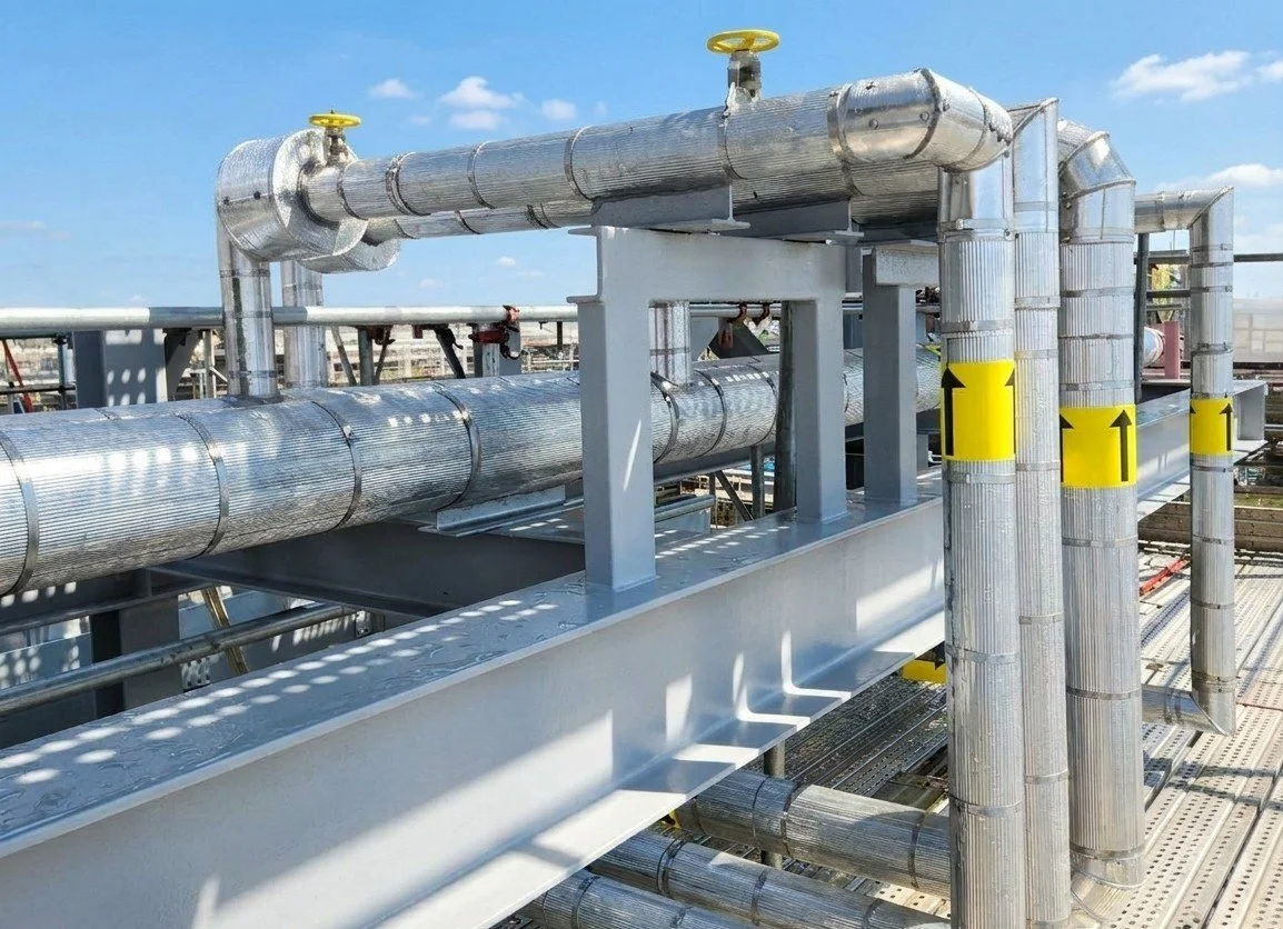 Industrial piping system with metal pipes and valves on industrial platform.
