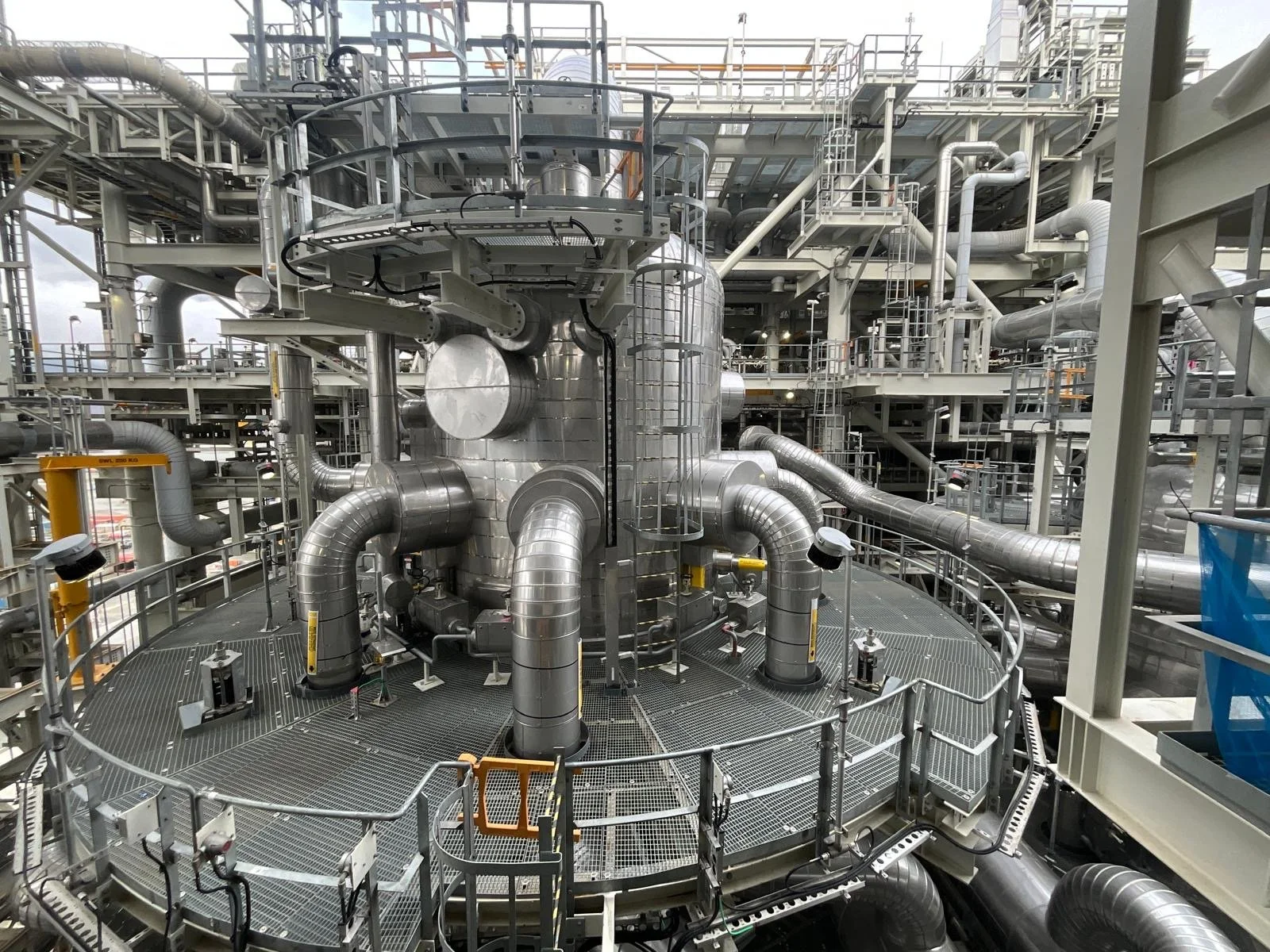 Industrial plant with metallic pipes and structural metal framework.