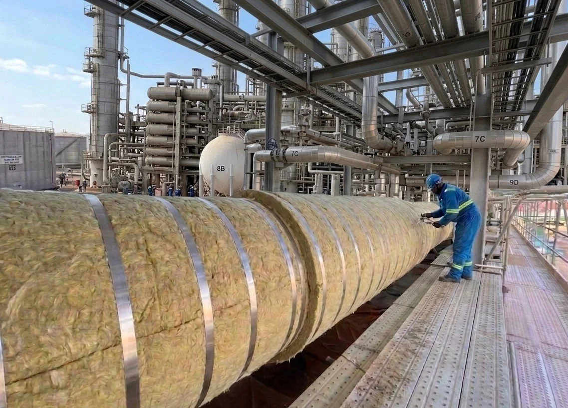 Installation of mineral wool (rockwool) insulation on a large bore pipeline.