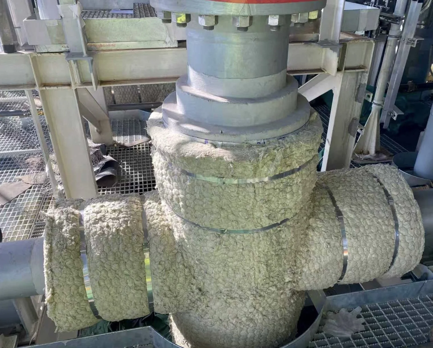 Galvanized wire mesh mineral wool pipe wrap being installed on large bore piping from Westcan Thermal Inc.