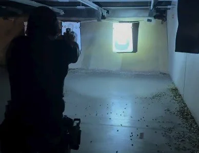 A person taking a photo or video of a shooting target in an indoor shooting range.