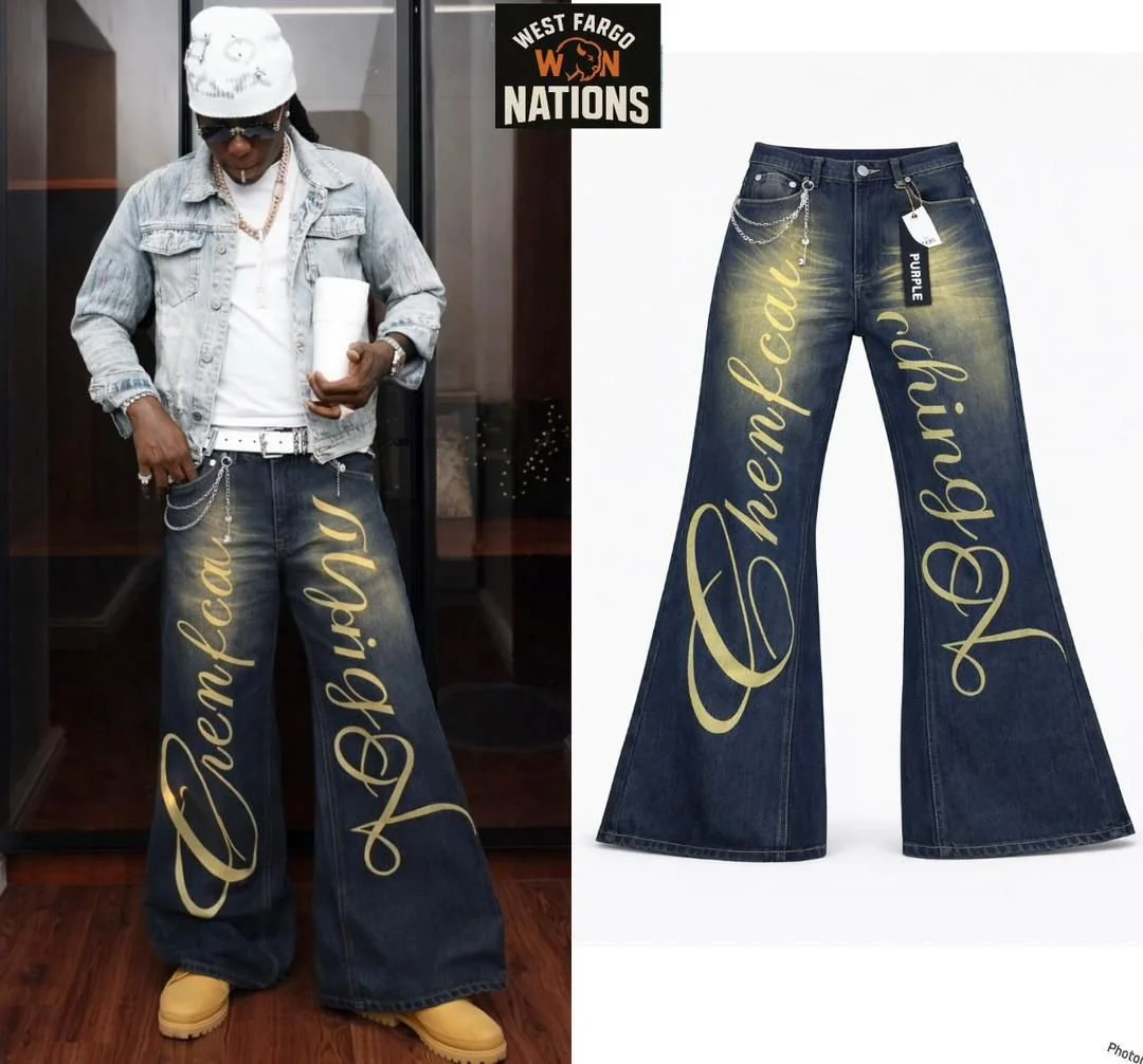 Person wearing wide-leg jeans with gold cursive text reading 'Cherish' and 'Refla', paired with a denim jacket, white shirt, yellow boots, and accessories. The jeans are displayed on a white background.