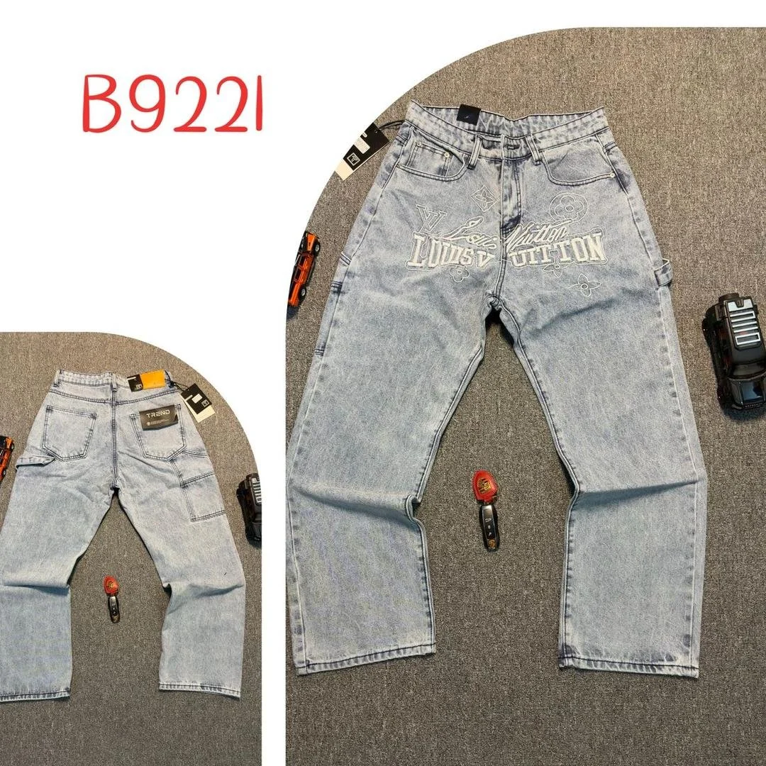 Two pairs of light blue denim jeans with various tags and tools around, one shown from the front and the other from the back, on a gray carpeted surface.