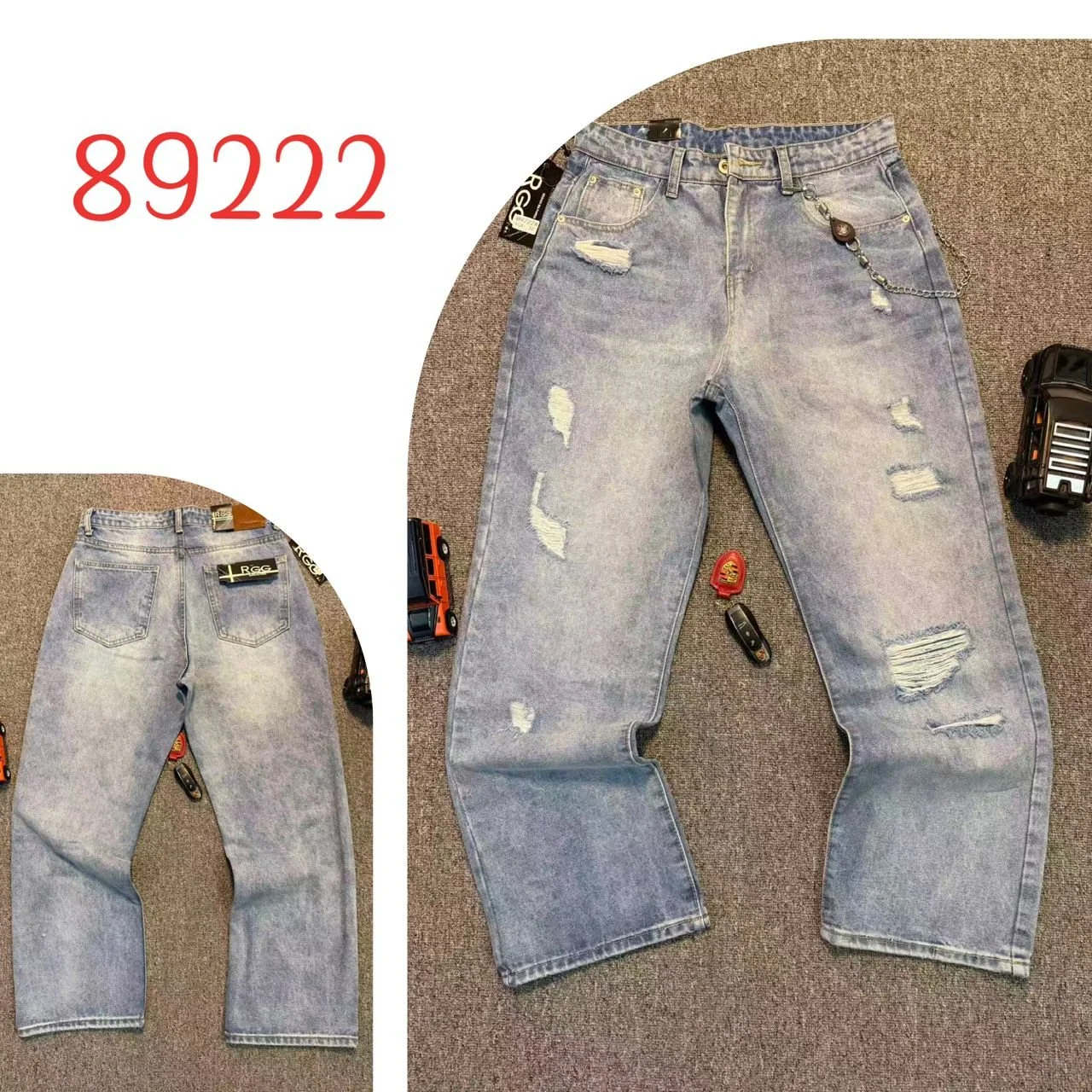 Pair of distressed, light-wash jeans laid flat on a gray carpet floor, with a keychain hanging from the belt loop and various remote controls placed around.