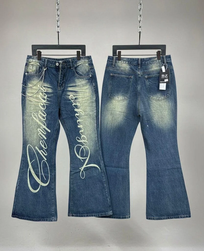 Pair of blue denim jeans on hangers, with one pair having white script text reading 'Deliciously Beautiful' and a chain accessory, the other pair has tags attached.