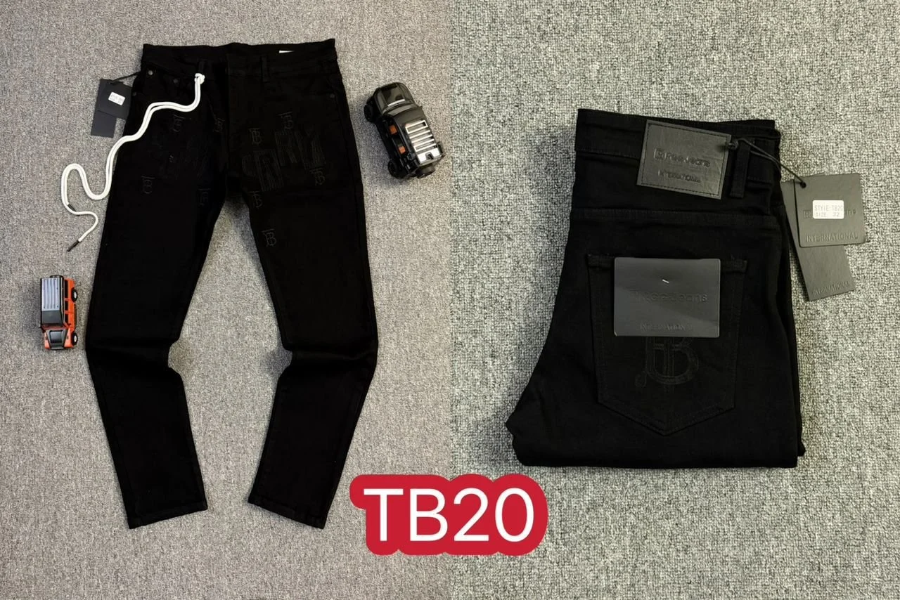 Pair of black jeans with tags on the right, and a pair of black pants with tags on the left, placed on a gray carpet. Two toy cars, one black and one orange, are positioned near the legs.