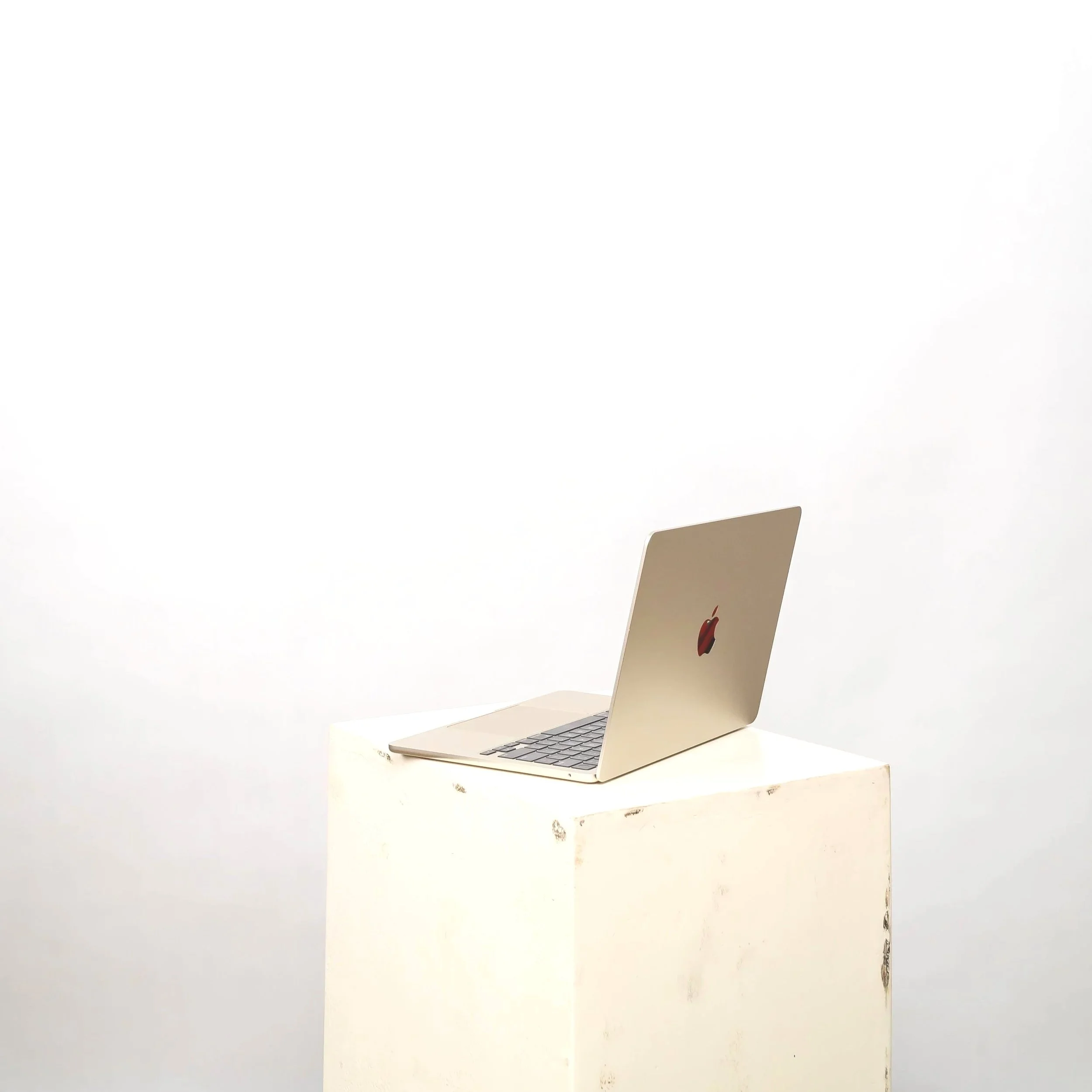 A silver MacBook laptop on a white surface in front of a plain white background.