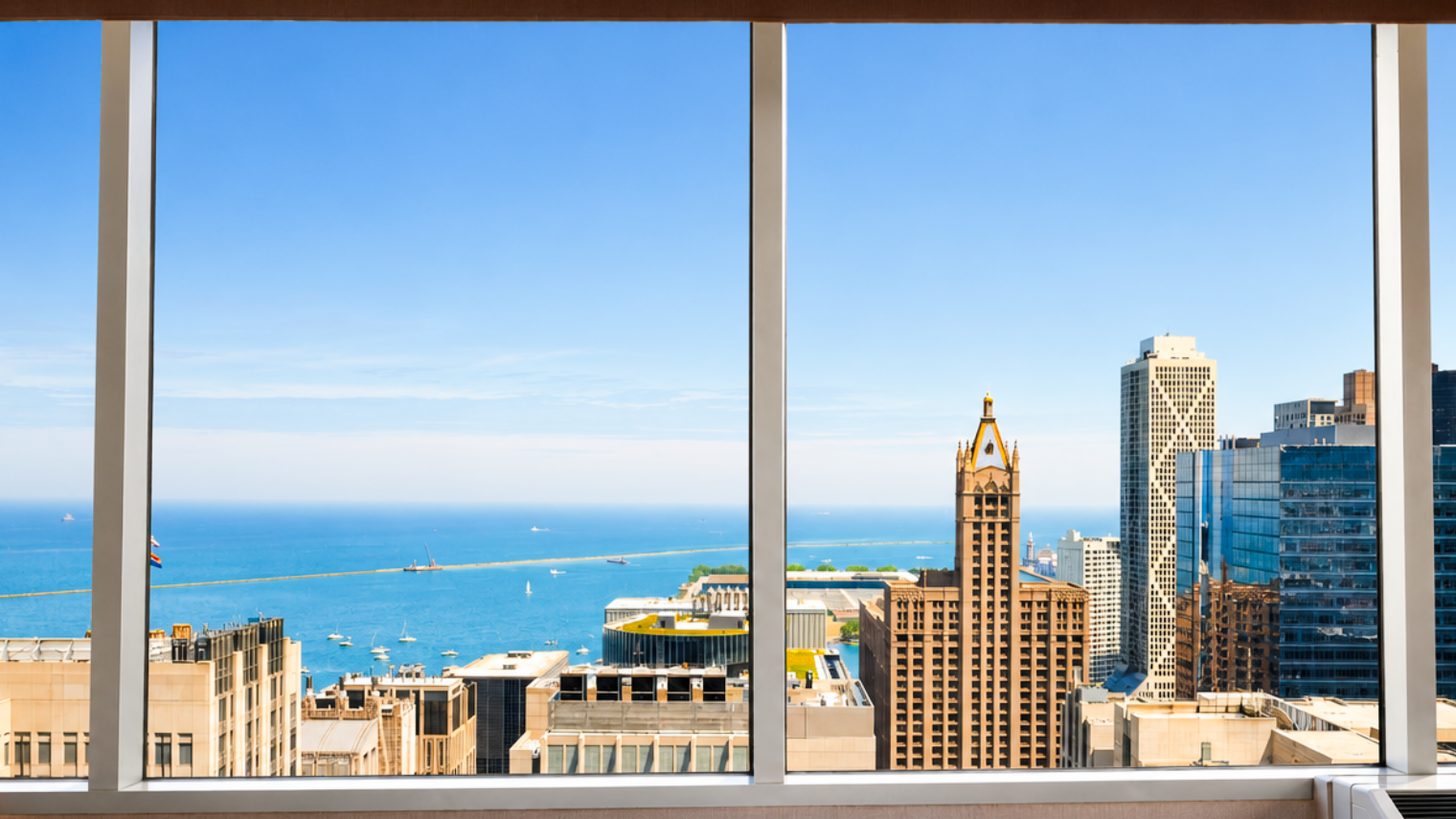 City skyline with tall buildings and a large body of water visible in the distance, seen from a window.